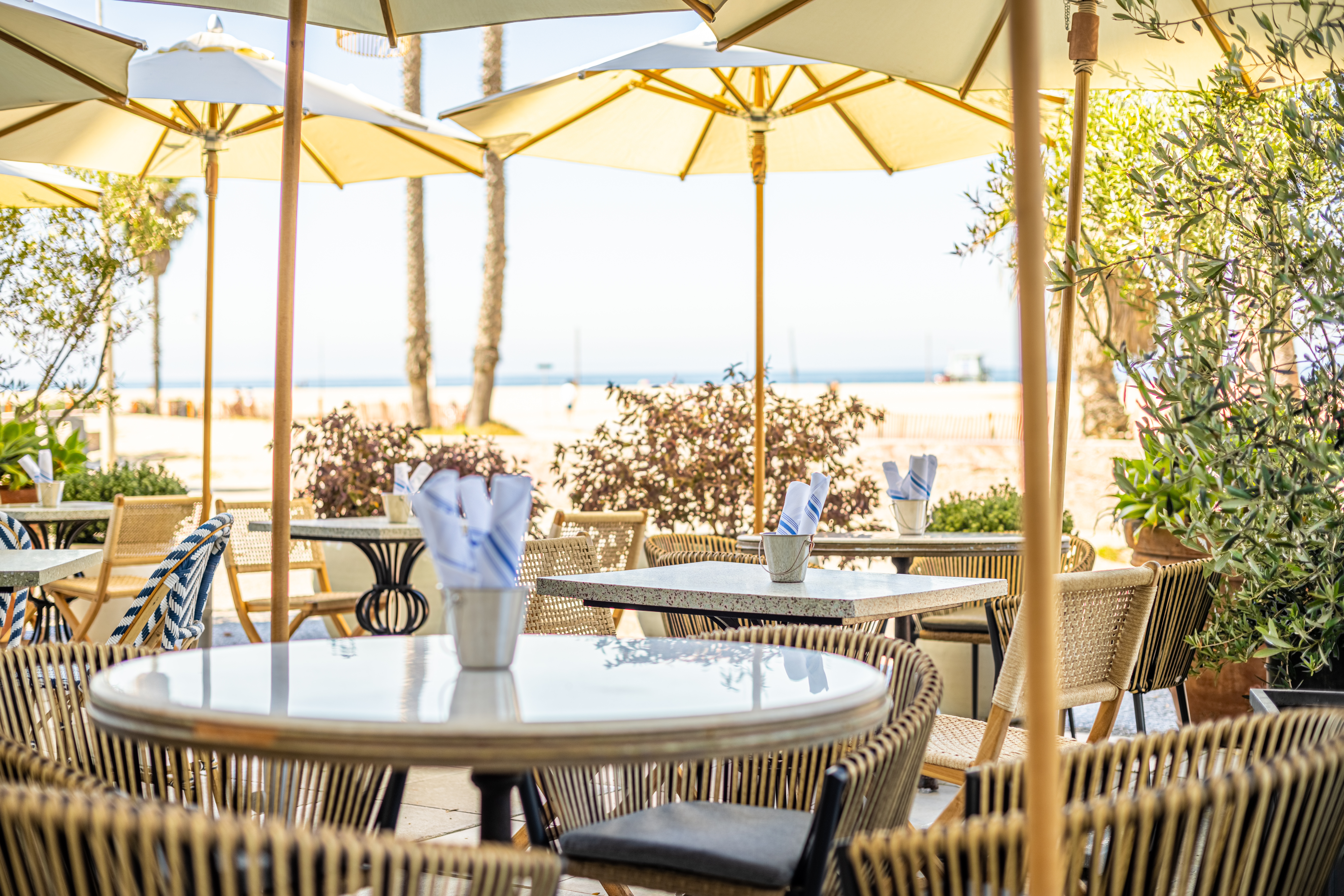 An outdoor patio area with tables and chairs for dining right on the beach with oceanfront views.