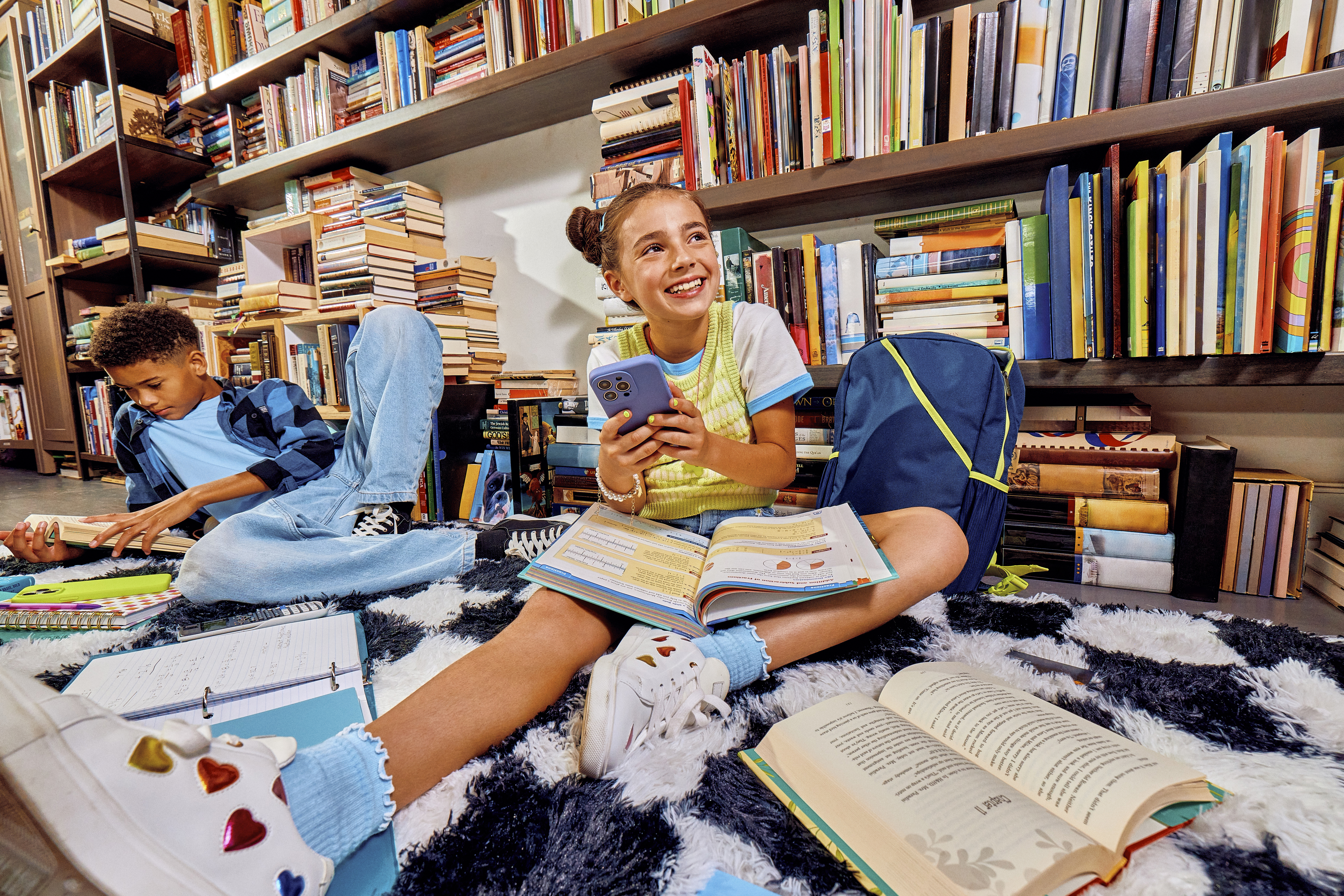 Teen sitting on floor in front of bookshelves