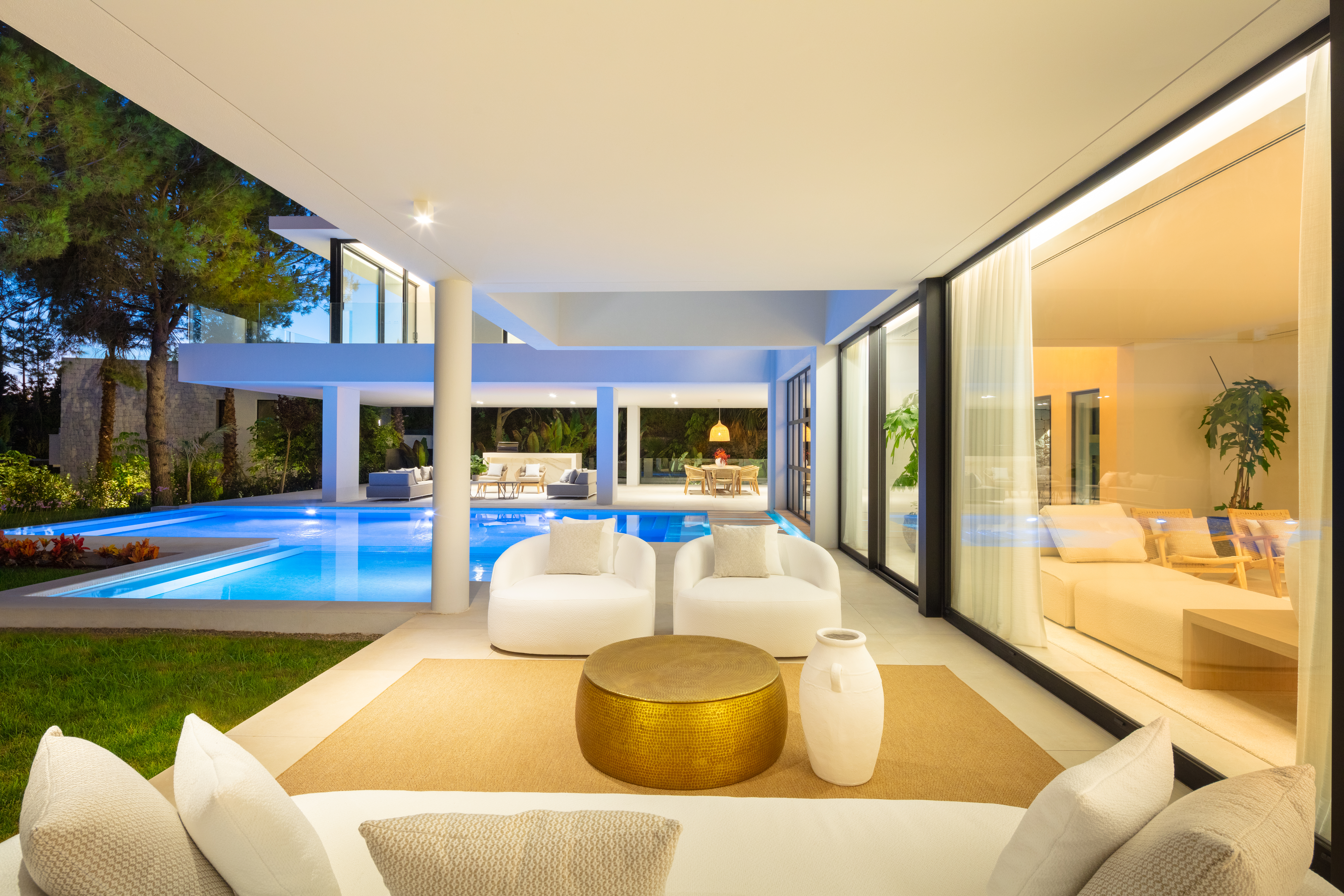 a white patio with couch and luxiourious pool