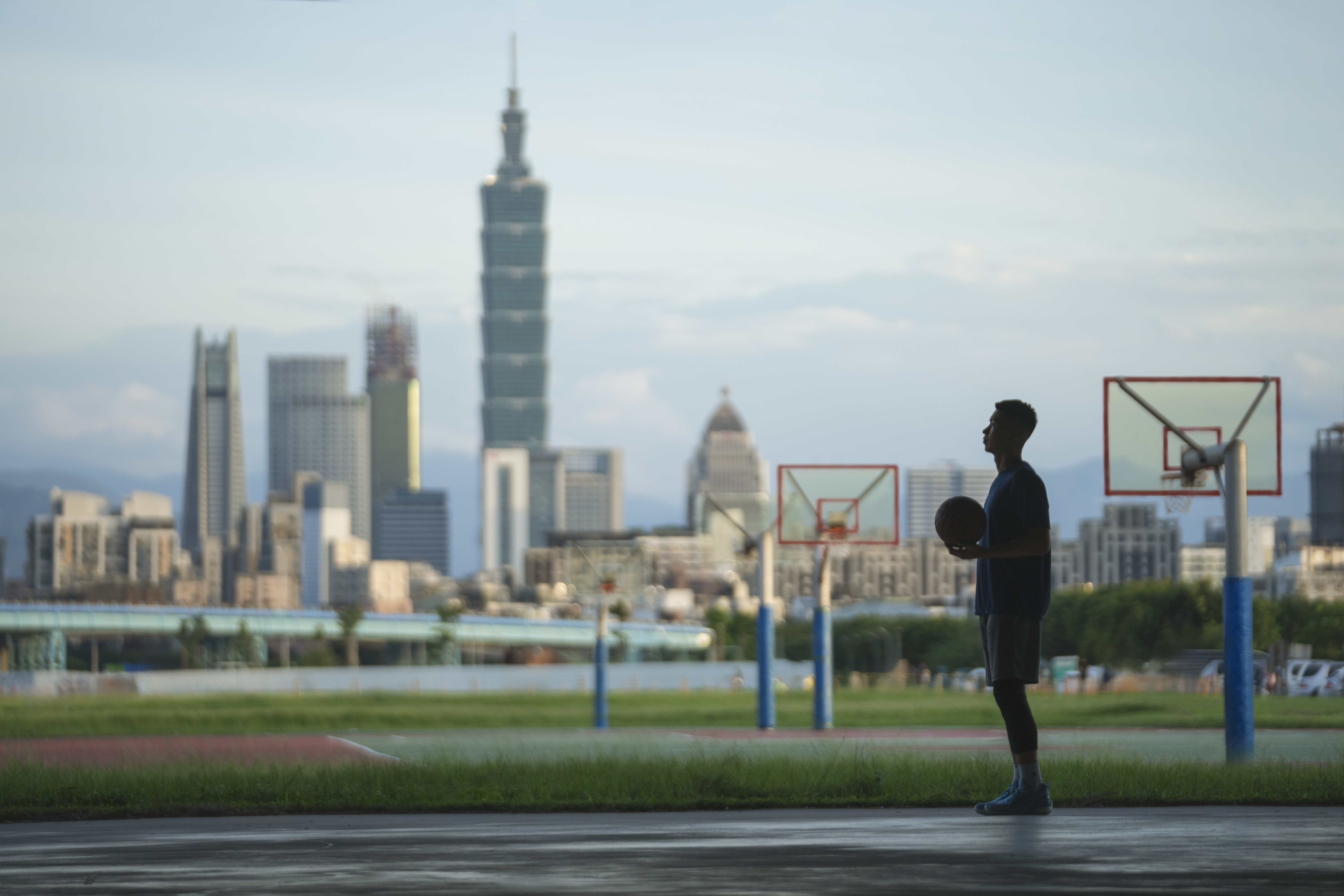Silhouette of Jeremy Lin holding basketball, city skyline behind
