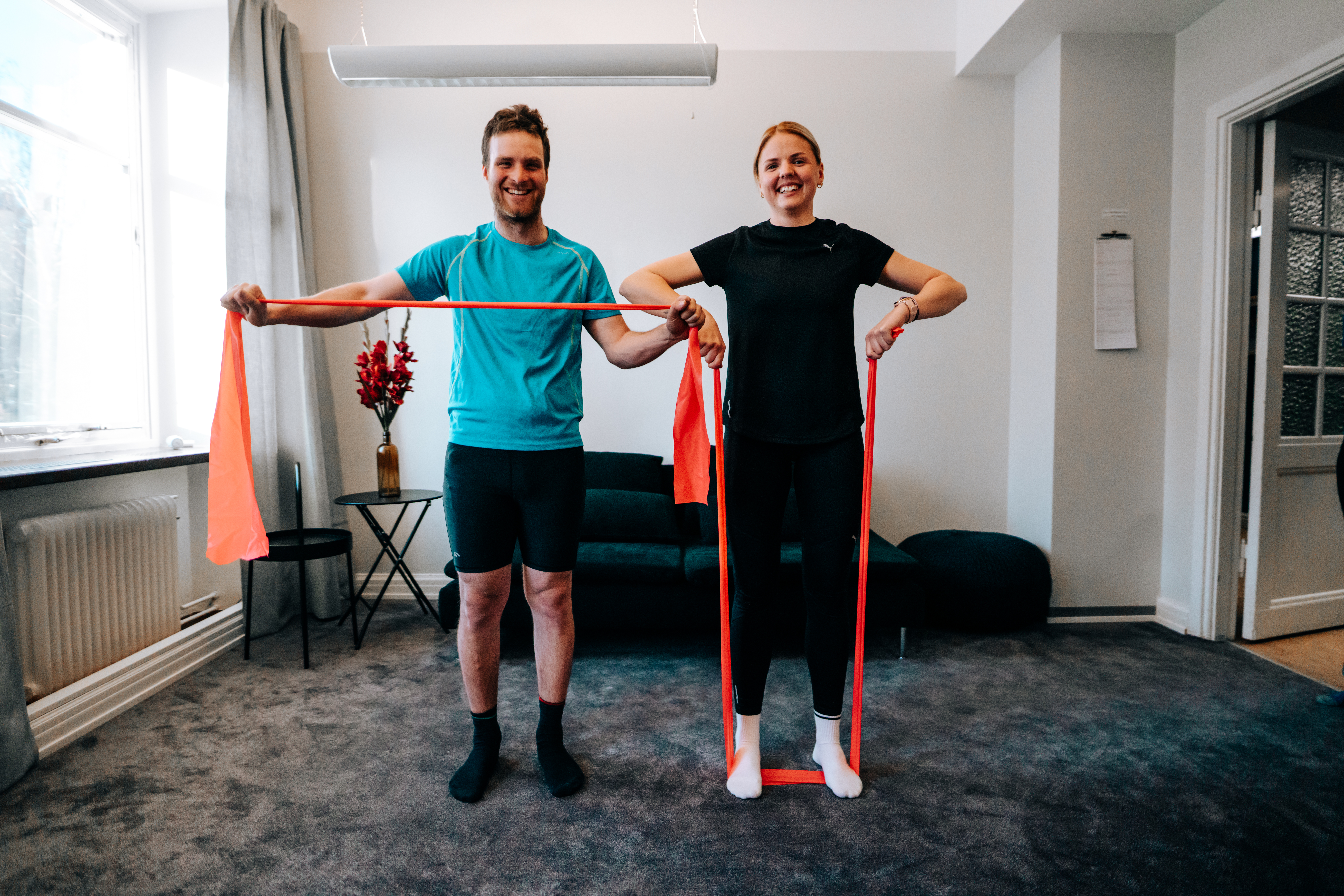 En man och en kvinna står bredvid varandra. De håller i gummiband på olika sätt för att visa olika övningar.