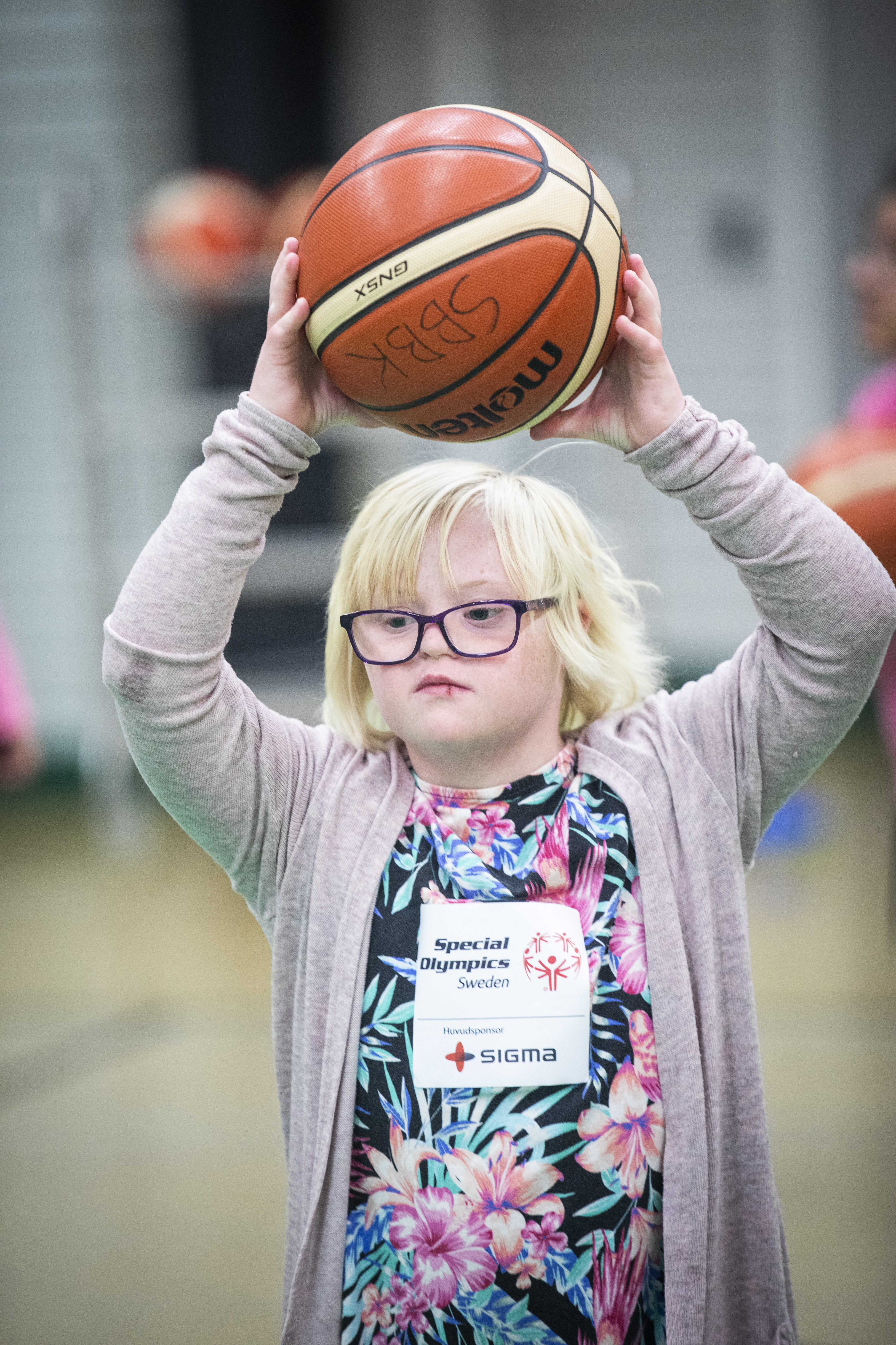 Flicka gör sig redo att kasta basketboll över huvudet.