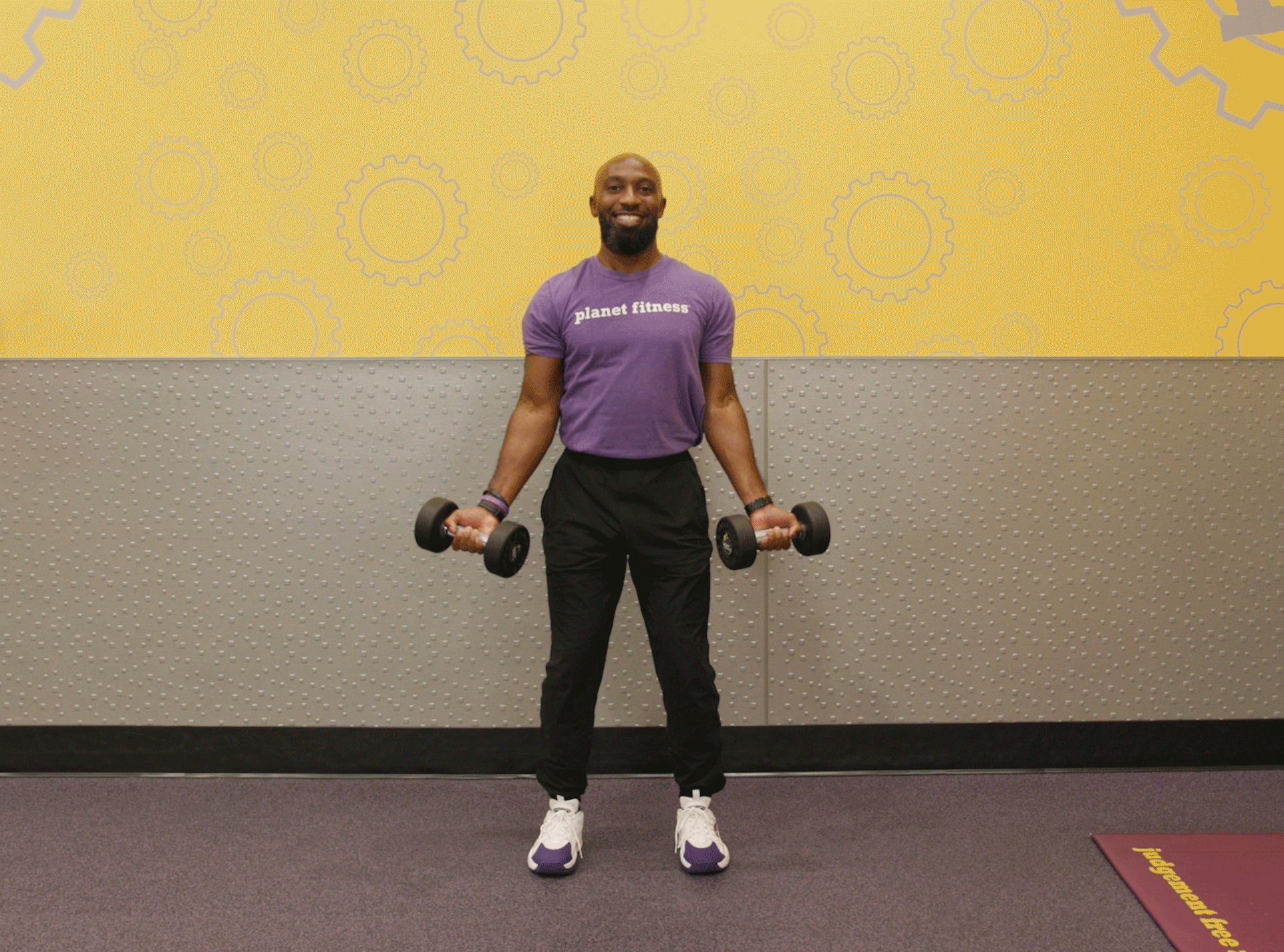 Man performing biceps curl exercise with dumbbells in Planet Fitness club