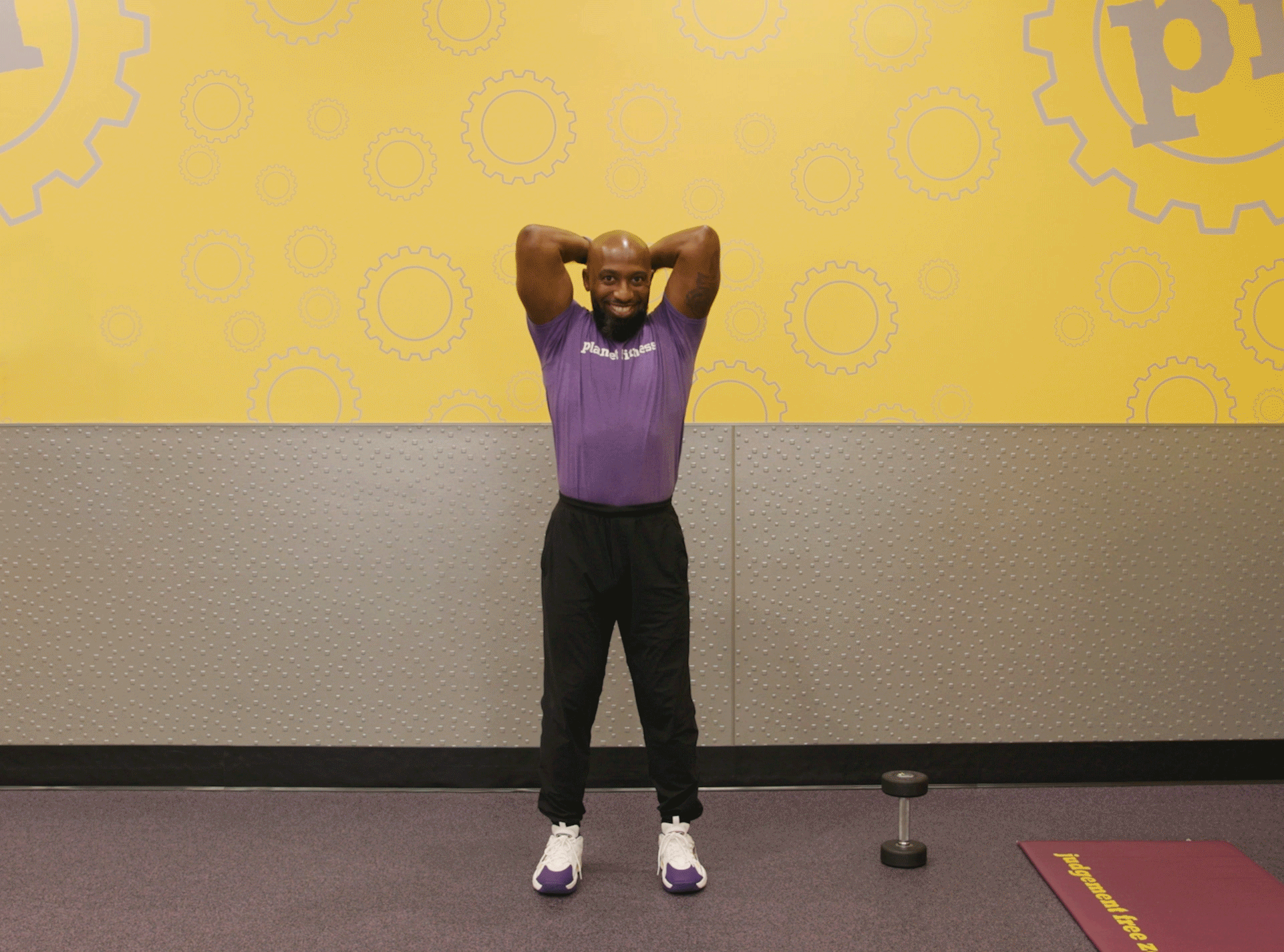 Man performing triceps extension exercise with dumbbells in Planet Fitness club