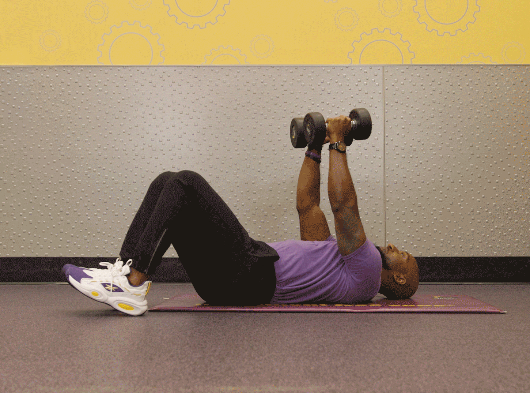Man performing lying chest fly exercise with dumbbells in Planet Fitness club