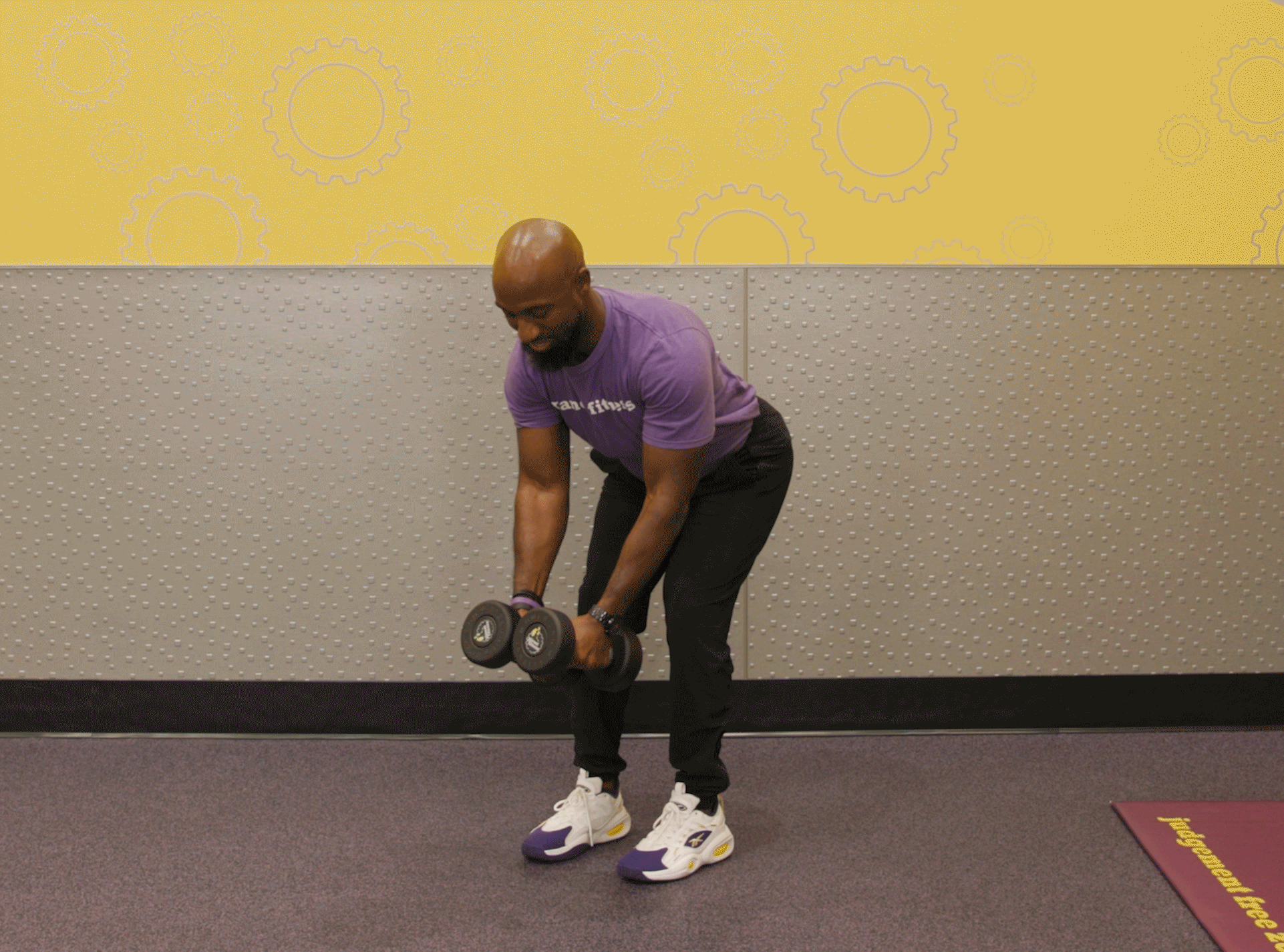 Man performing reverse fly with dumbbells in Planet Fitness club