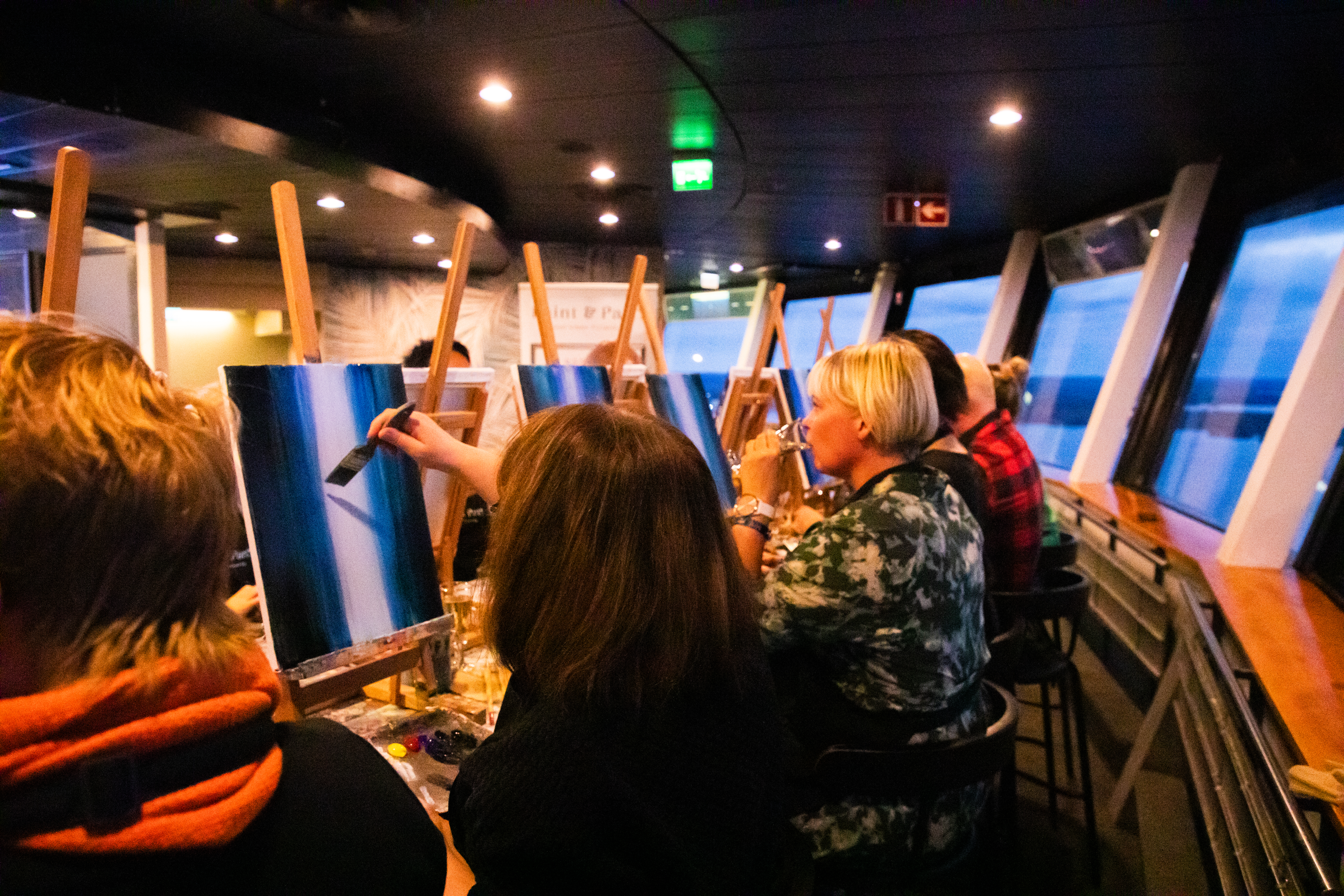 Ryhmä maalareita maalaa teoksia ja nauttii virvokkeita Neula Sky Cafessa.