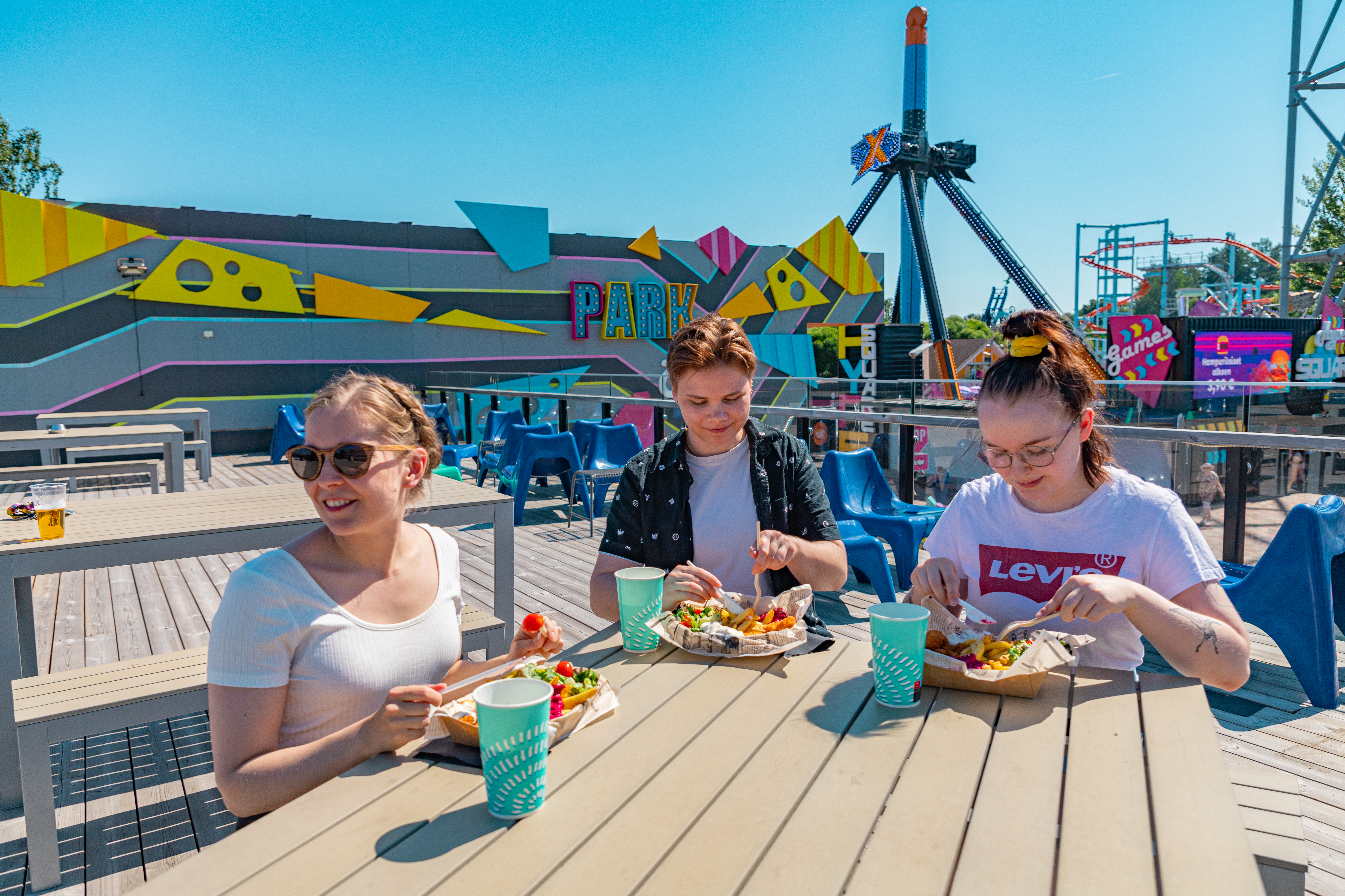 Kolme iloista ihmistä ruokailemassa Särkänniemessä.