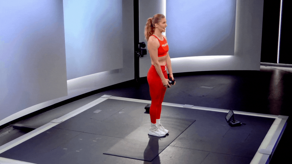 Peloton instructor Rebecca Kennedy demonstrates a standing bird dog exercise with a dumbbell