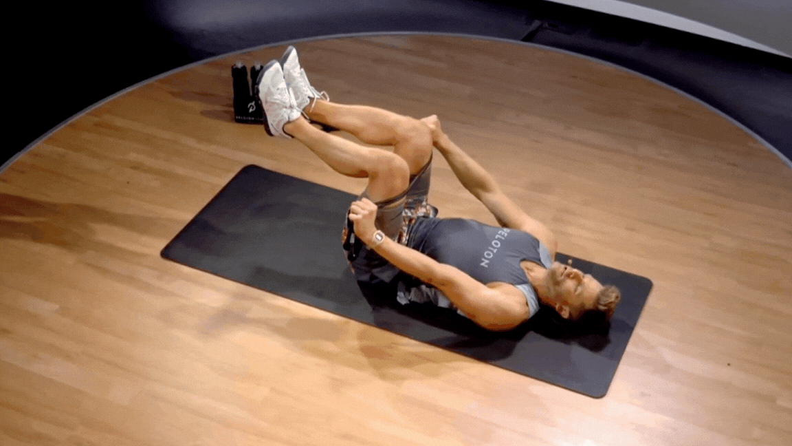 Peloton instructor Andy Speer demonstrates a resistance band hip flexor crunch.