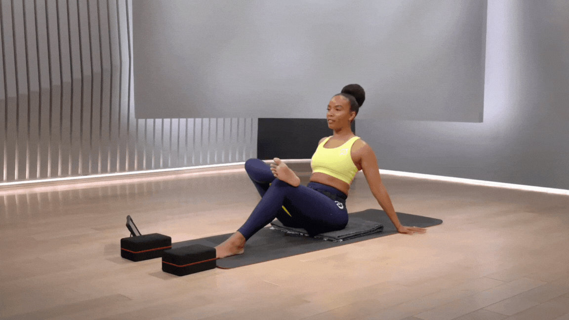 Peloton instructor Chelsea Jackson Roberts demonstrates a seated figure four morning stretch