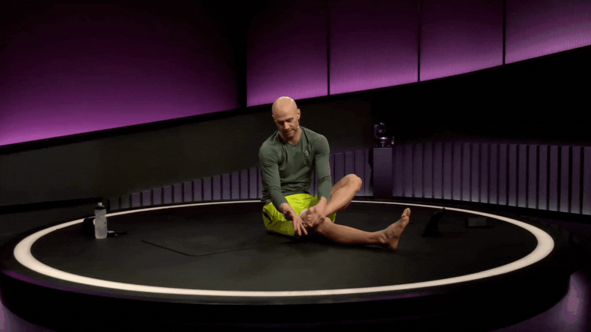 Peloton instructor Marcel Maurer demonstrates interlaced ankle circles during a feet and ankle mobility class