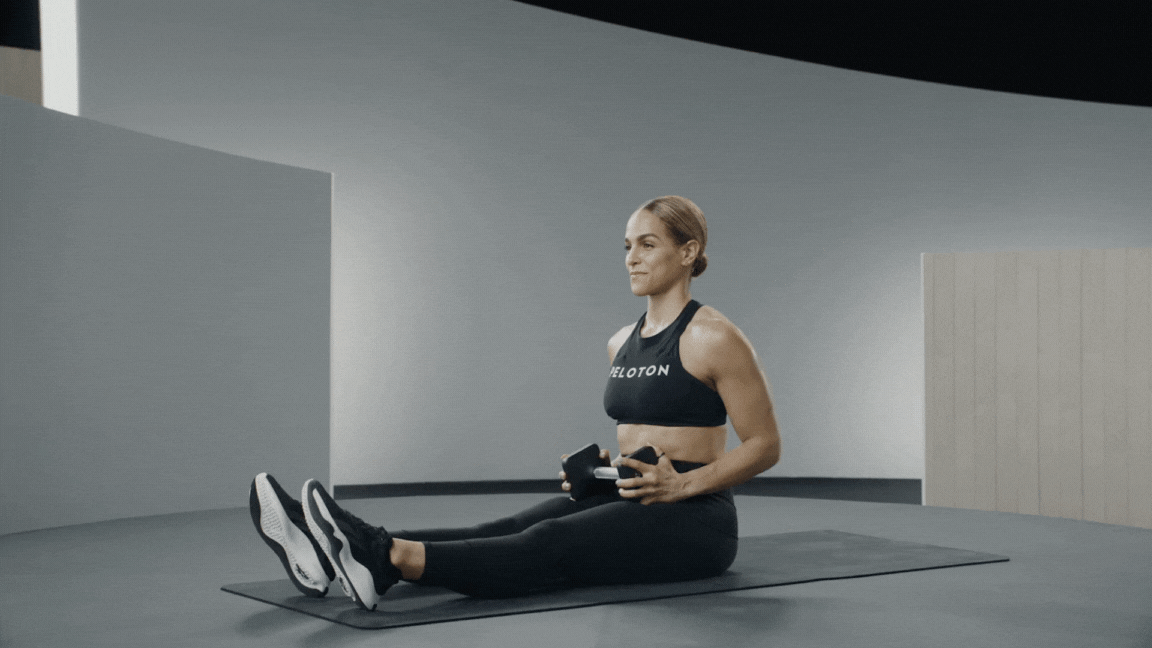Peloton instructor Jess Sims demonstrates a dumbbell Russian twist exercise for pickleball.