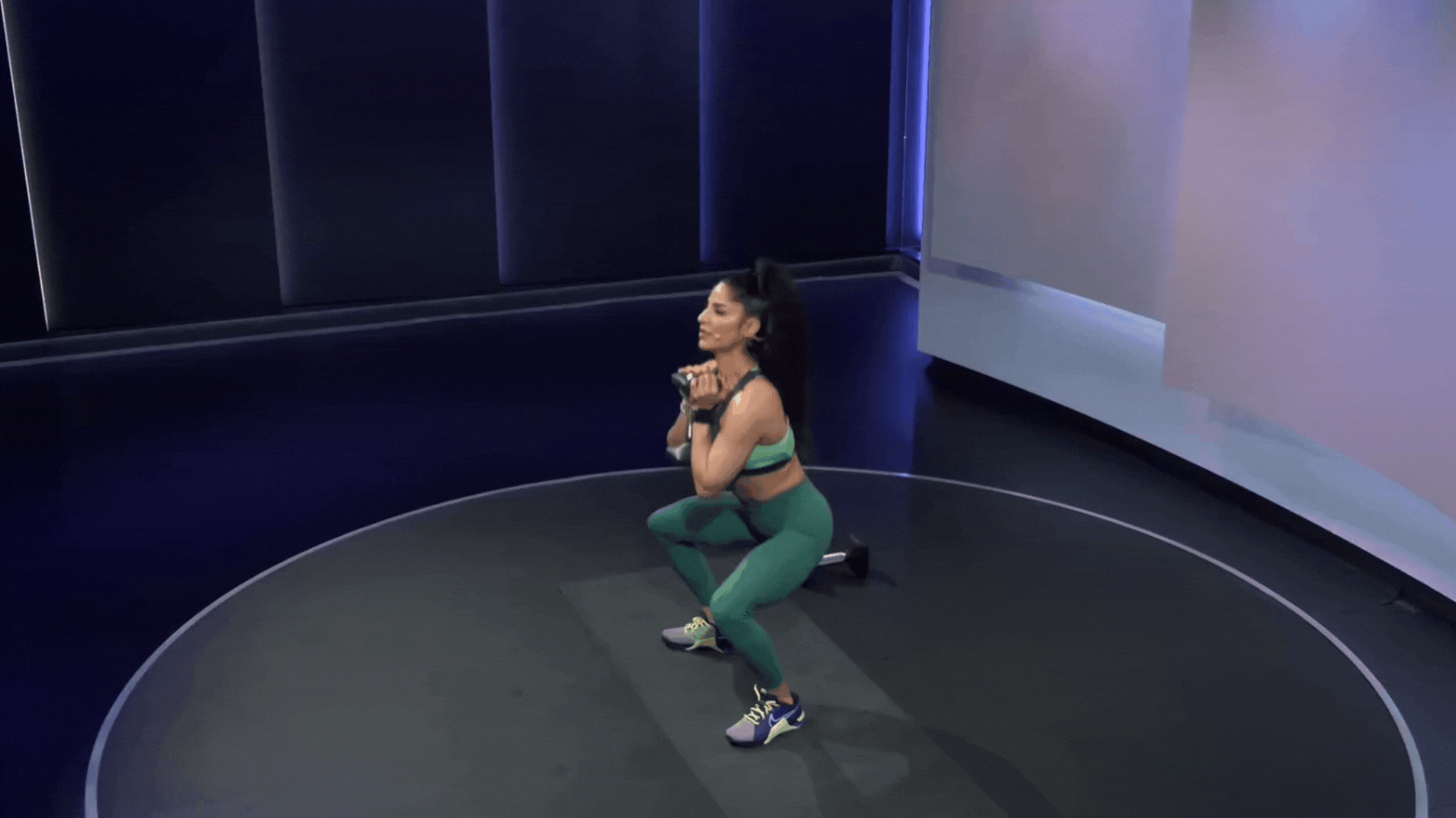 Assal Arian doing a squat holding a dumbbell 