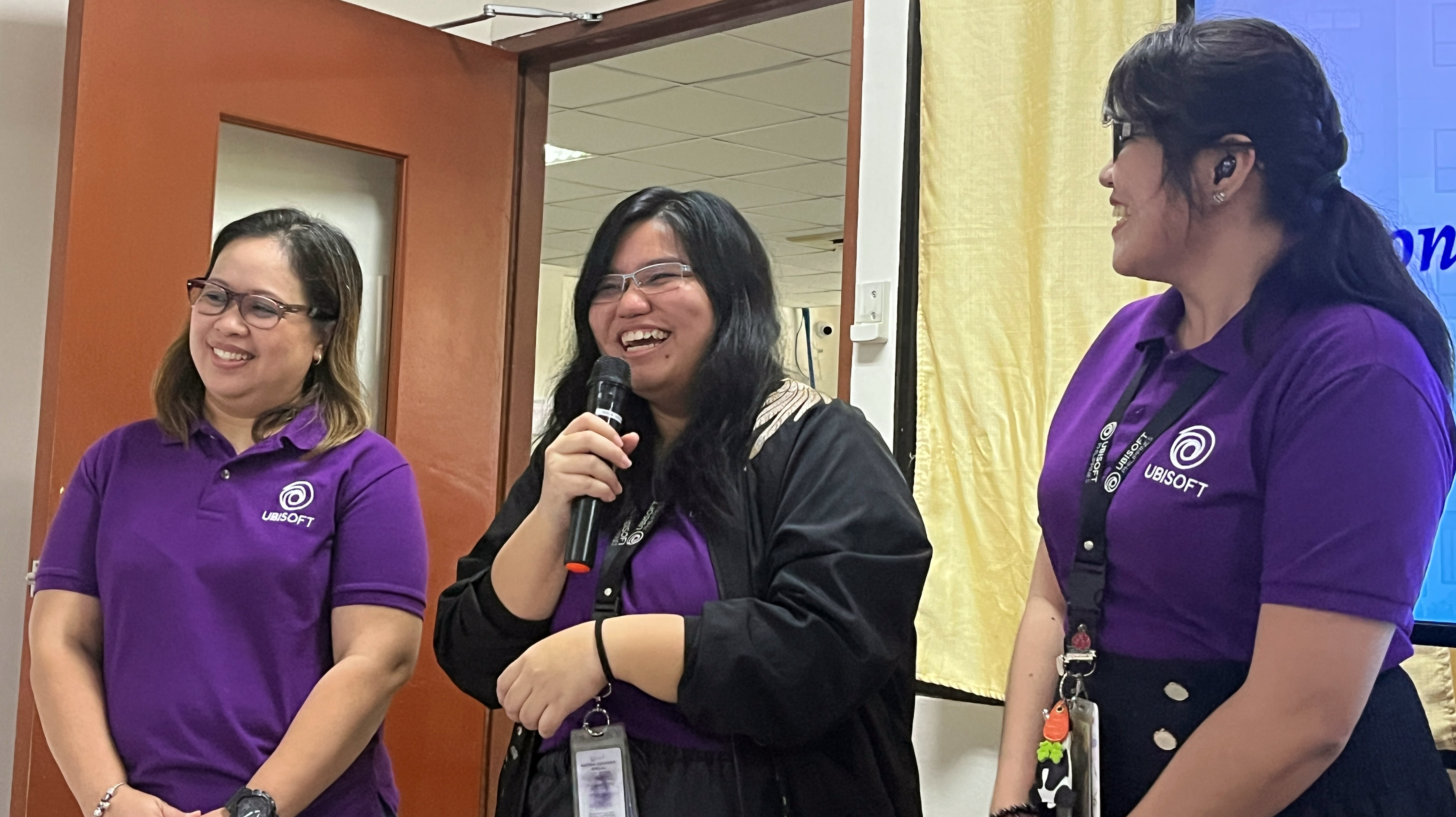 Three  smiling ubisoft team members sharing the microphone to present