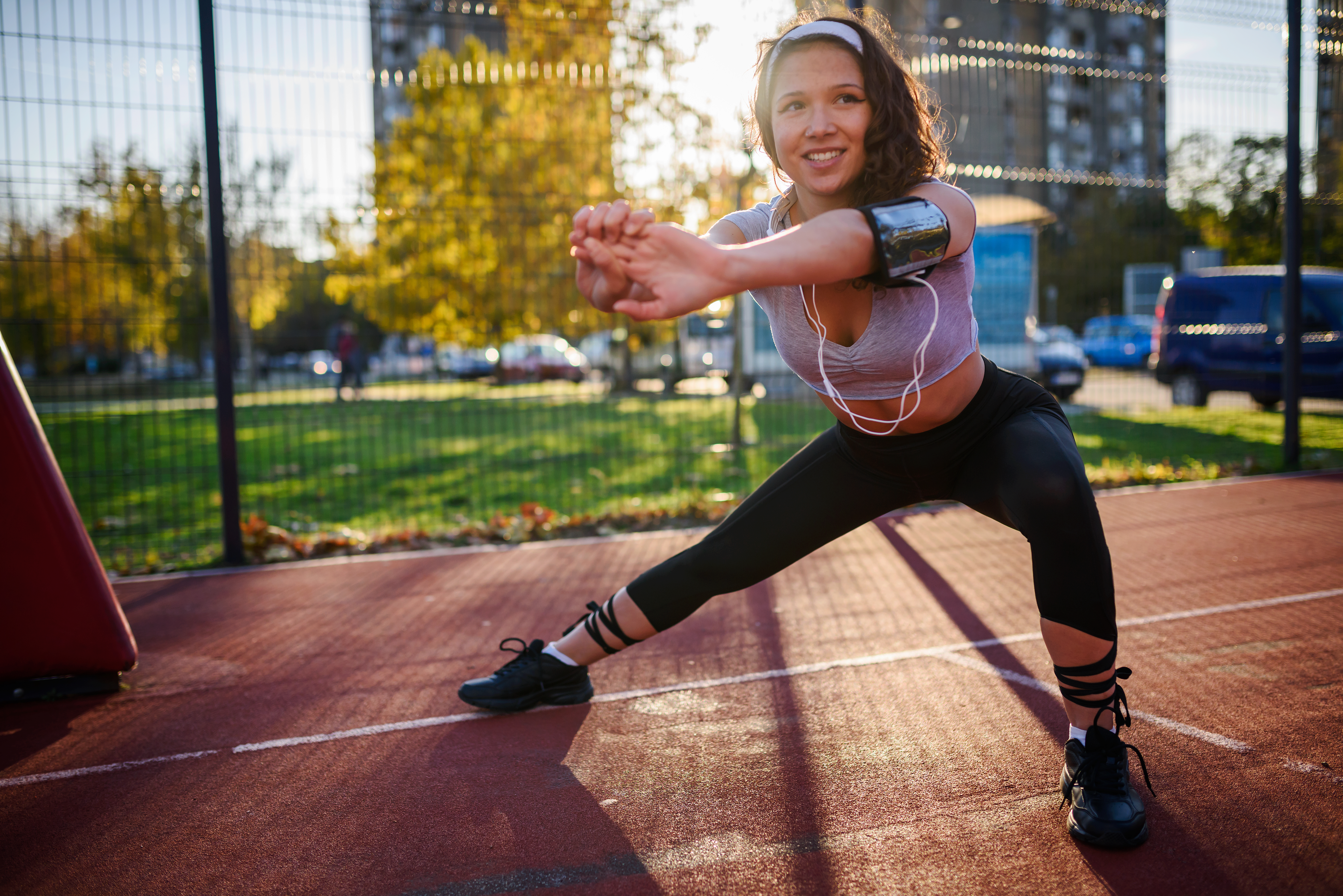 Girl doing a side squat at a running field during sunset