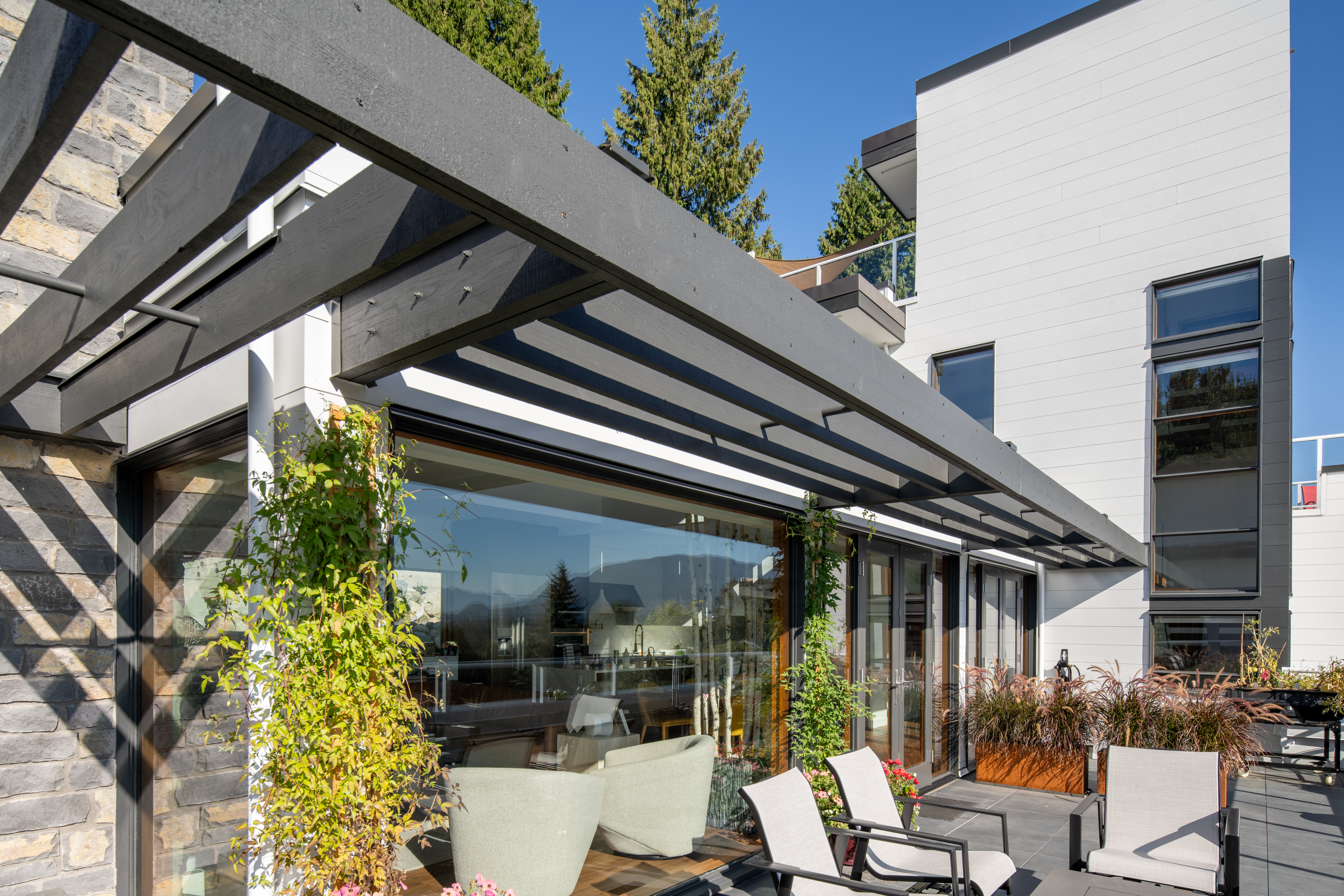 Rooftop deck featuring greenery and a glass sunroom. Building clad in Artisan lap siding.