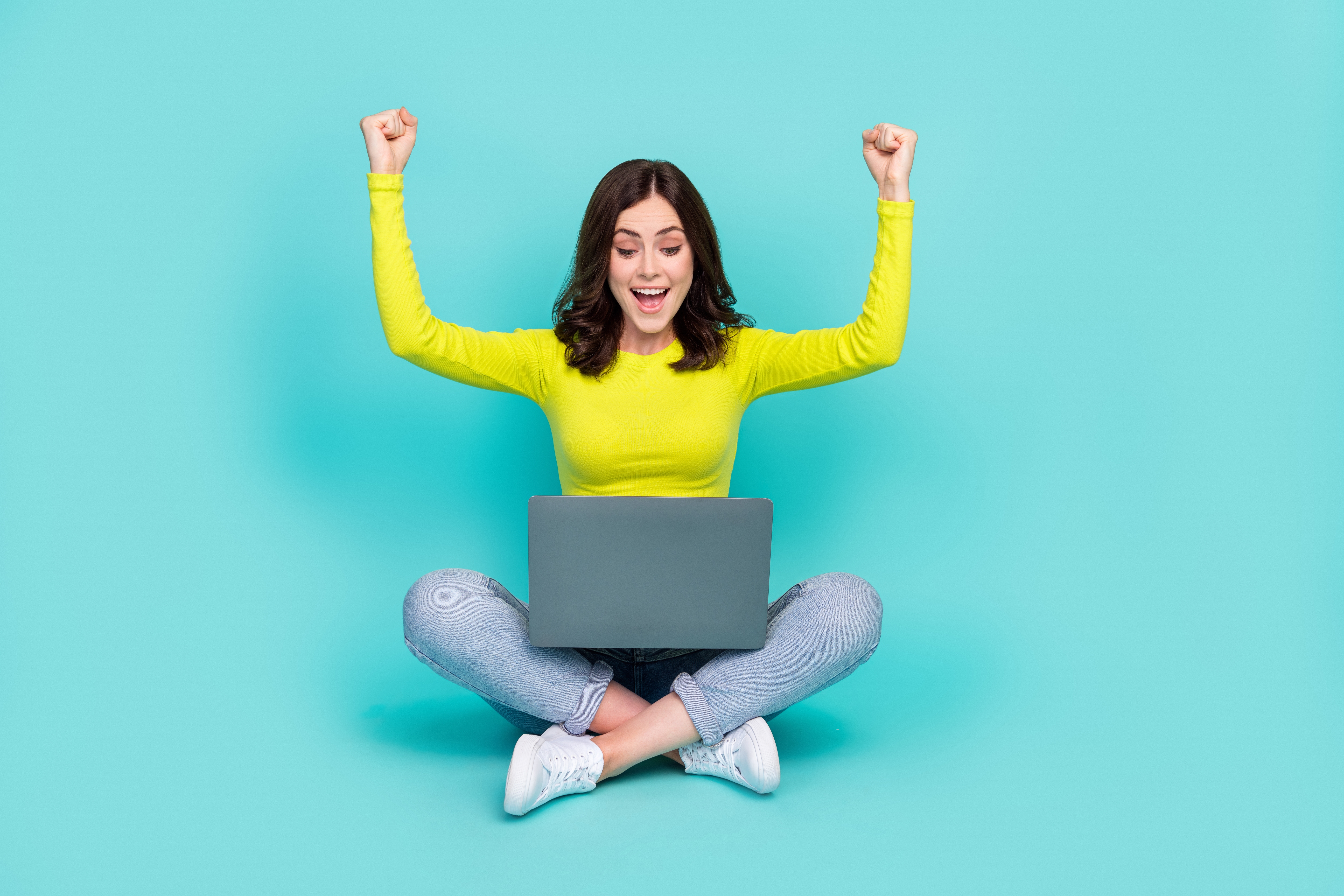 young woman looking pleasantly surprised and excited at something on her computer 