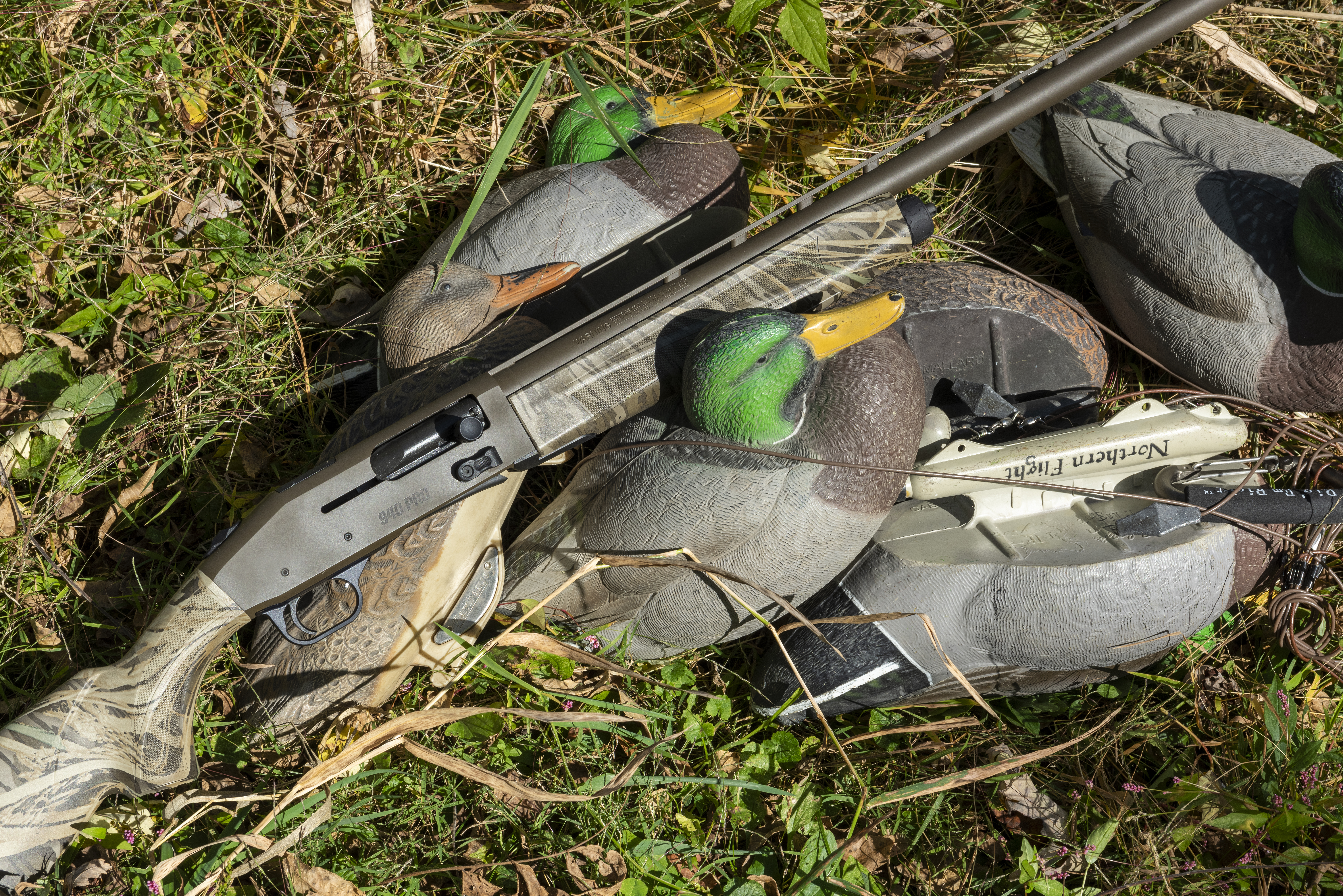 The new Mossberg 940 Pro Waterfowl lying in grass with duck decoys. 