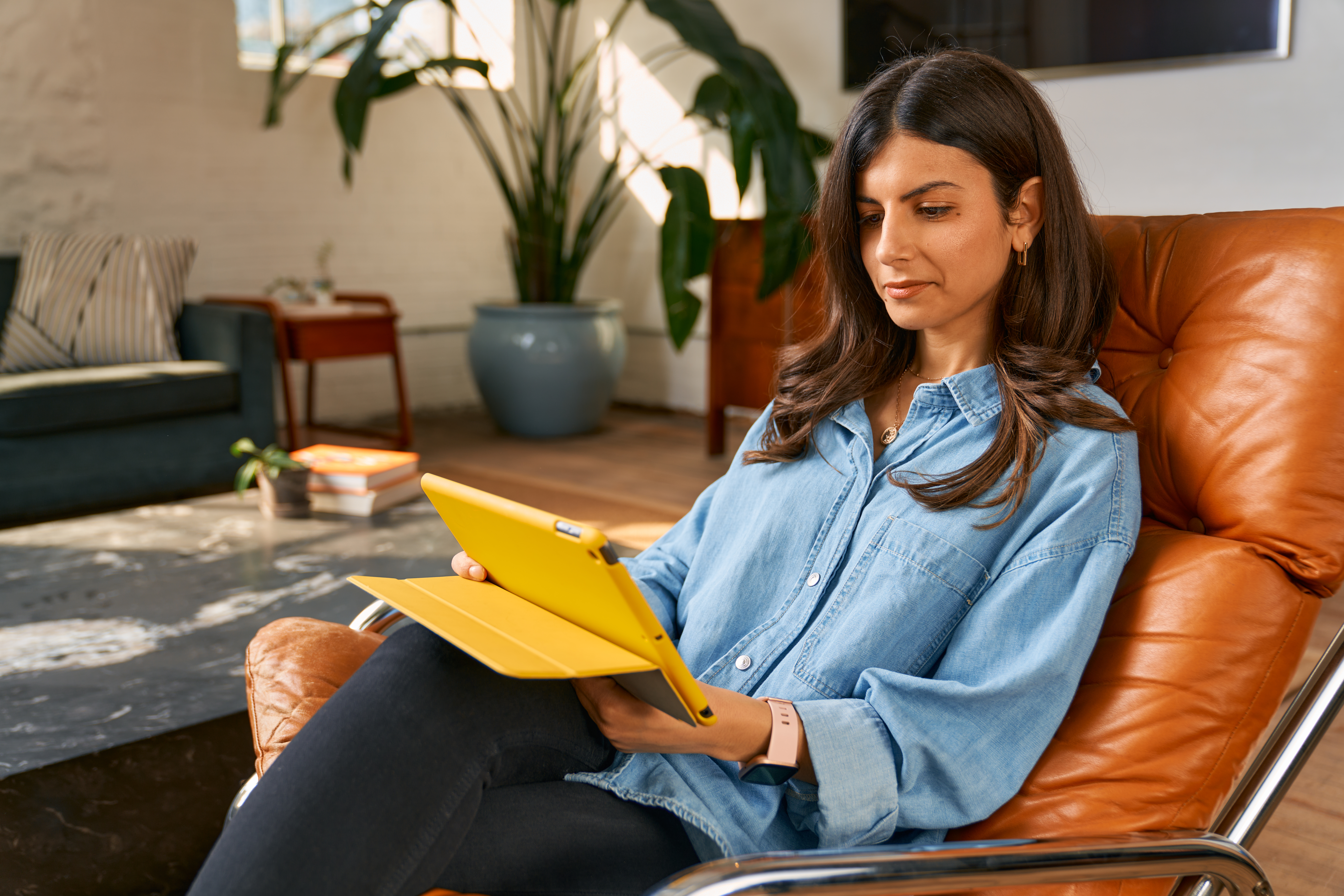 A woman on a leather chair with a yellow iPad
