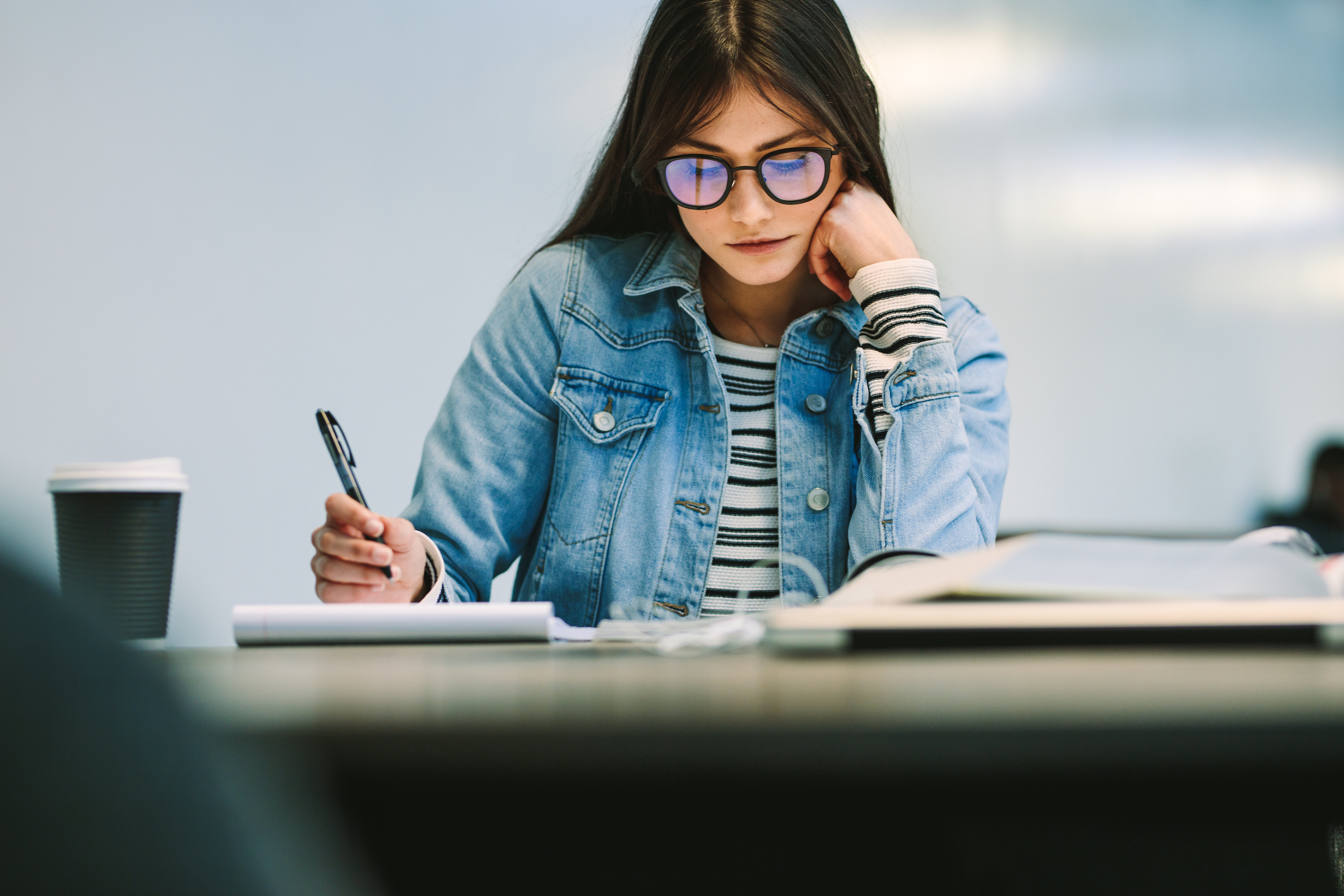 A focused female student is studying in a college library setting.