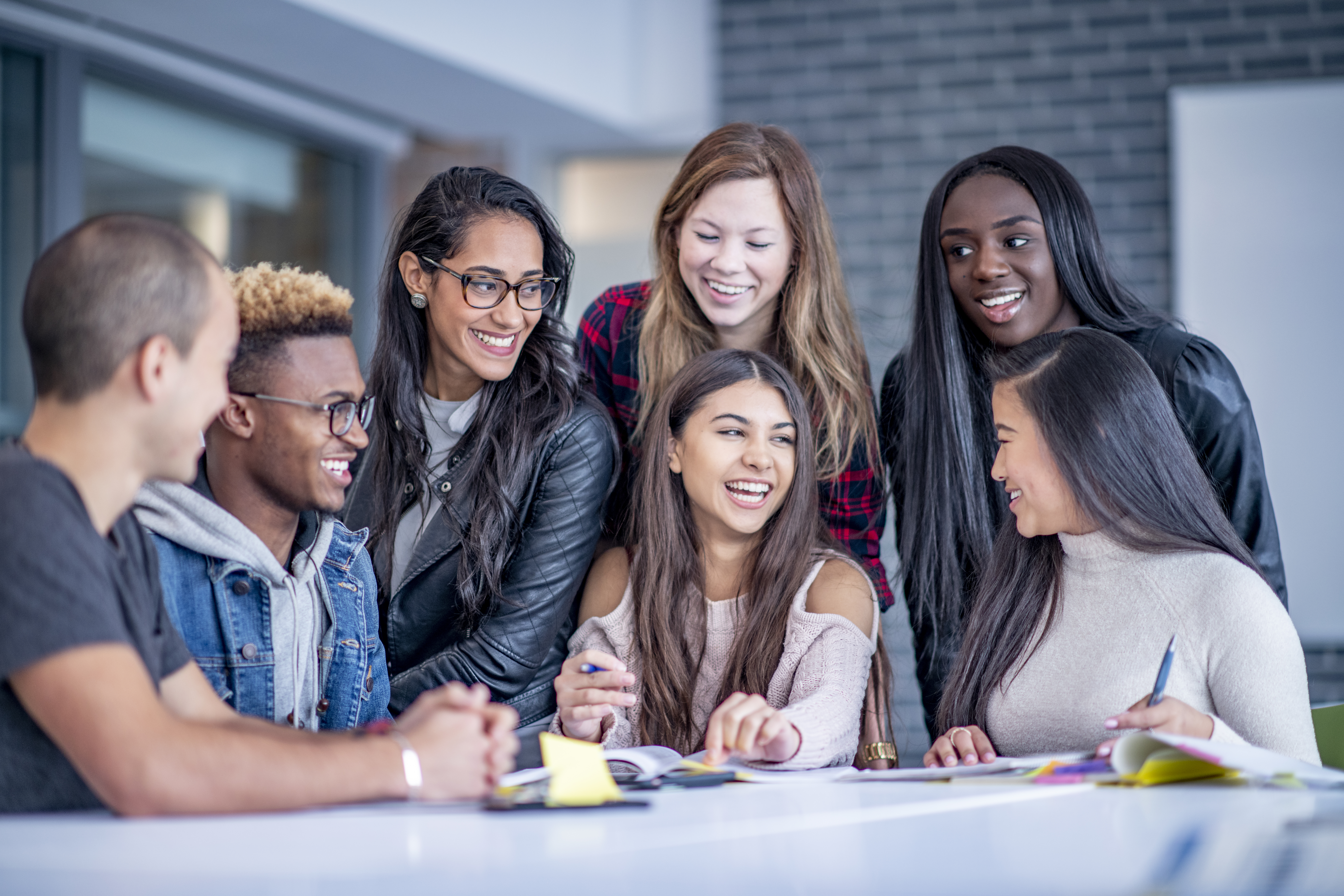 A diverse group of happy college students sitting around a table. iStock-1067477990