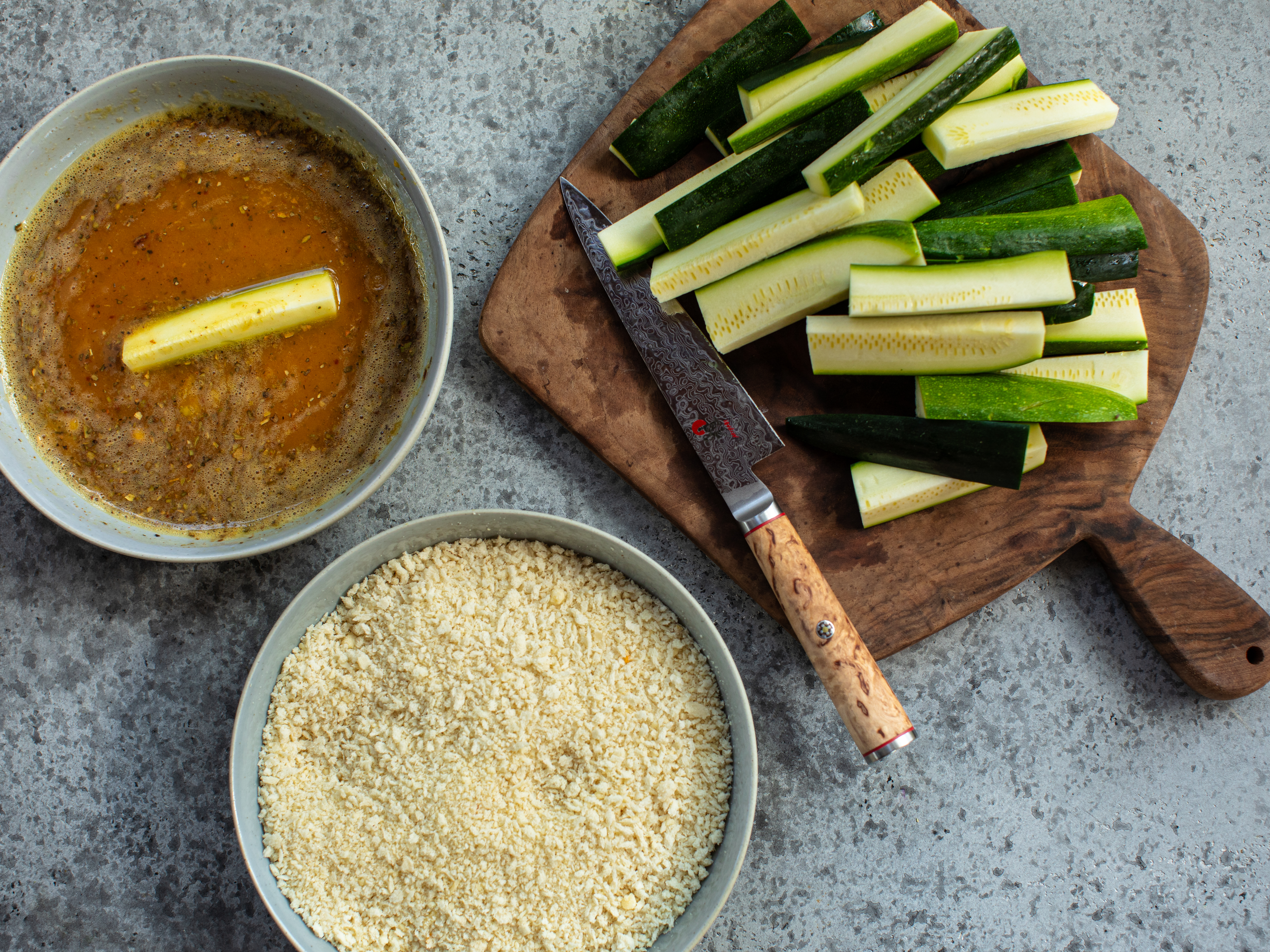 Schritt 2: Jede Zucchetti-Pommes zuerst in der Eimischung wenden und dann in der Panko-Paniermehl-Parmesan-Mischung gut panieren, sodass sie rundum bedeckt sind