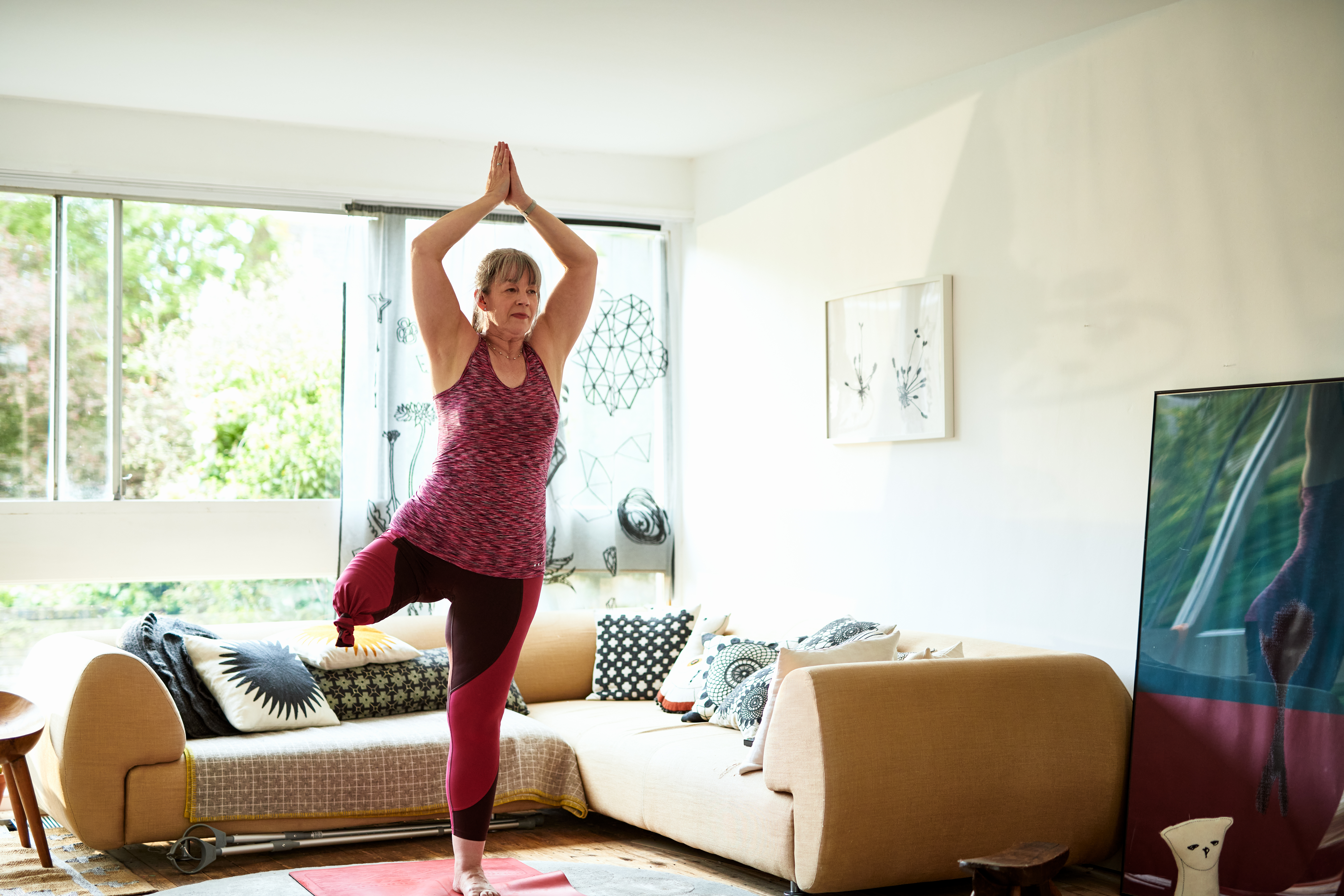 Woman in loungeroom standing on one leg in a yoga pose