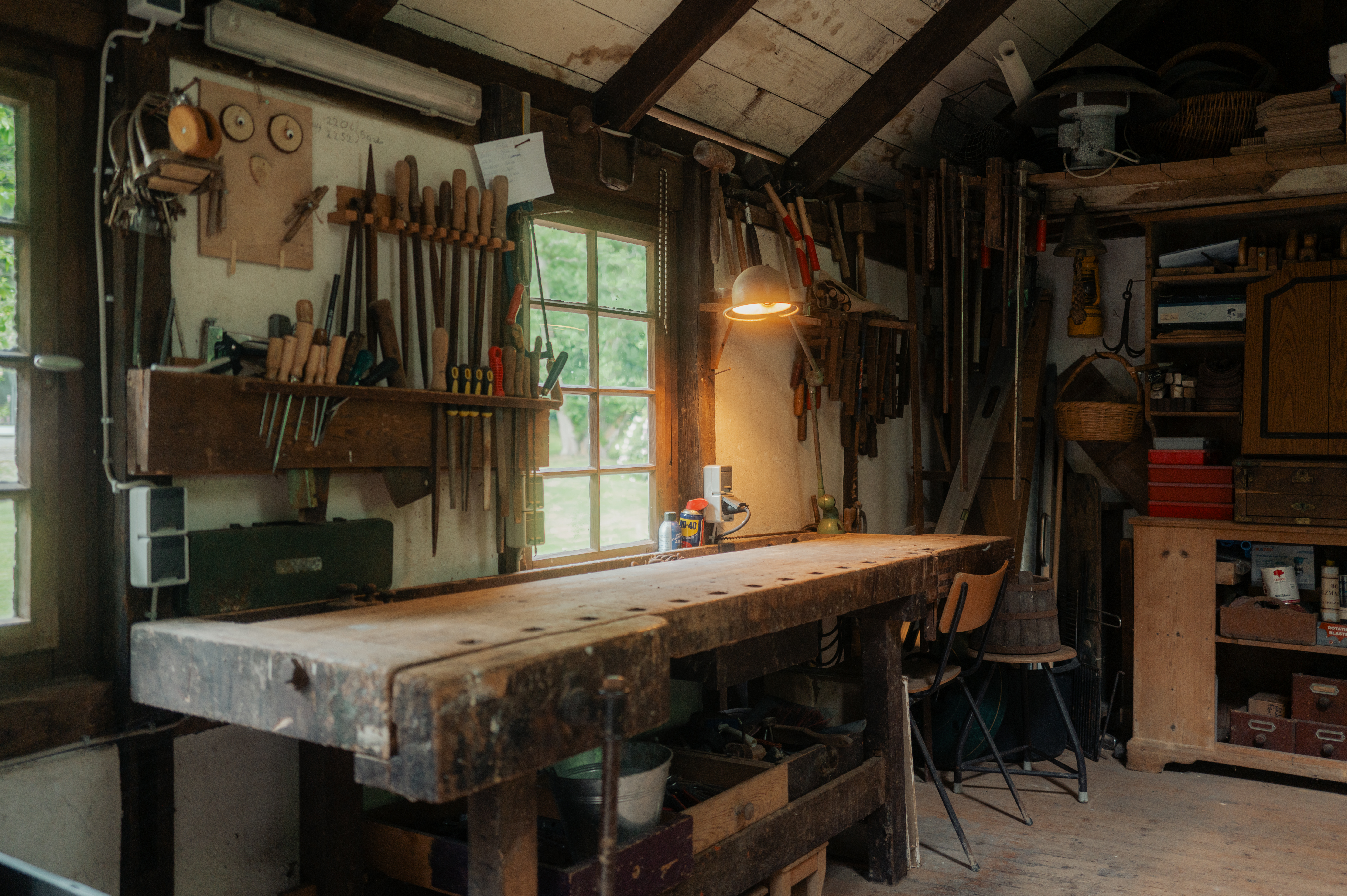 Werkstatt mit Werkbank, Werkzeugen an der Wand und Regalen mit verschiedenen Utensilien.