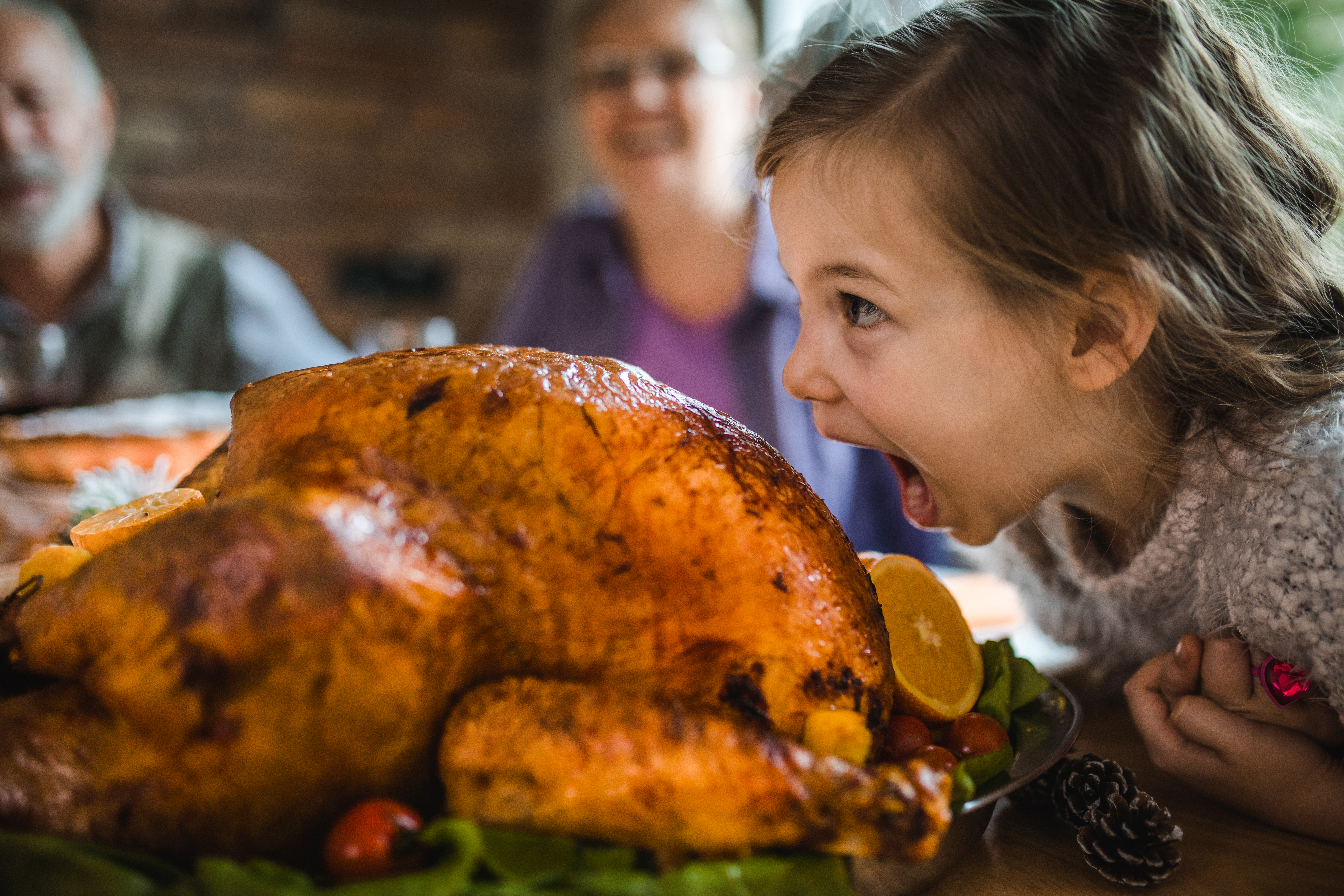 A child about to take a bite out of a roasted turkey.