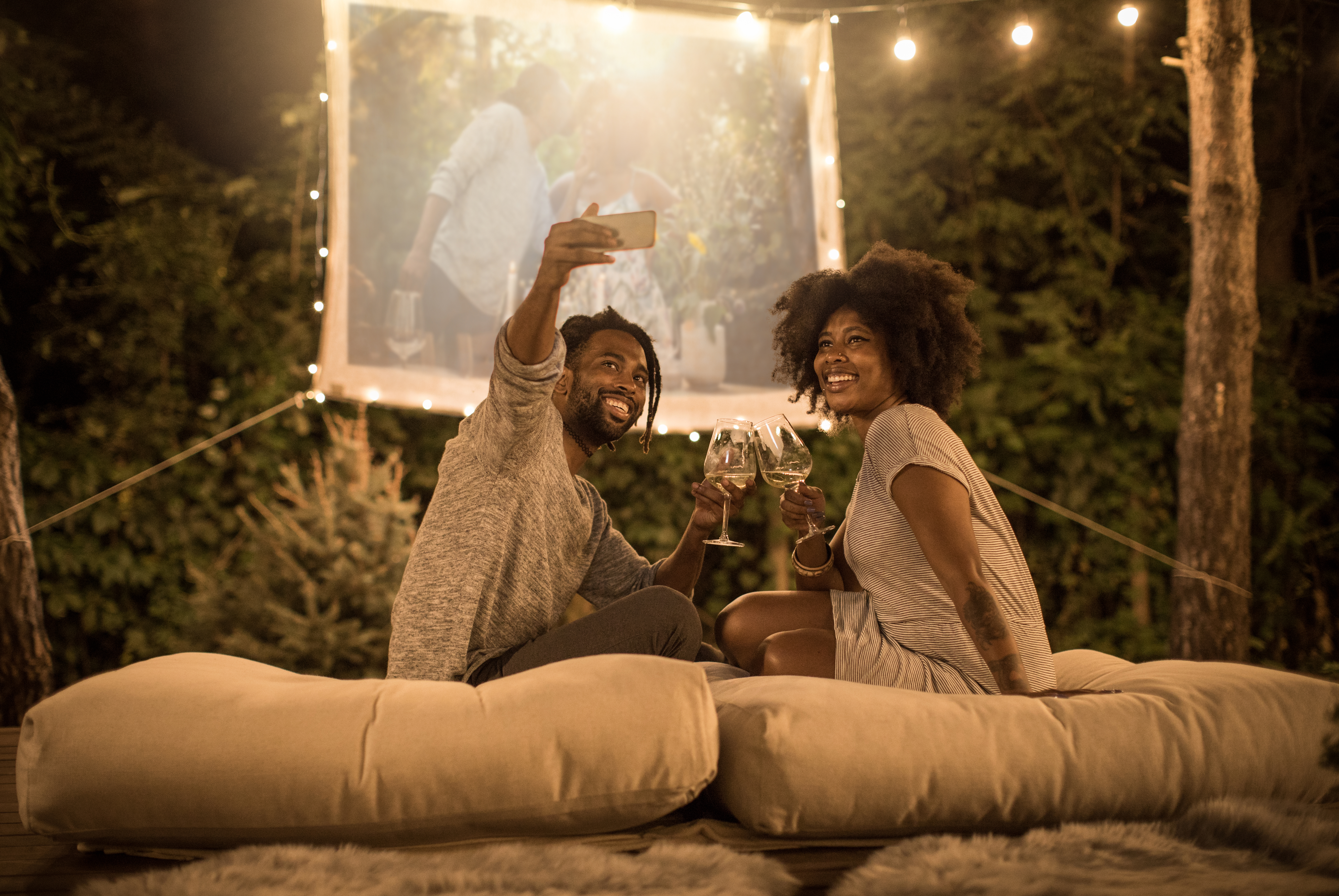 Couple enjoying outdoor movie while sipping wine