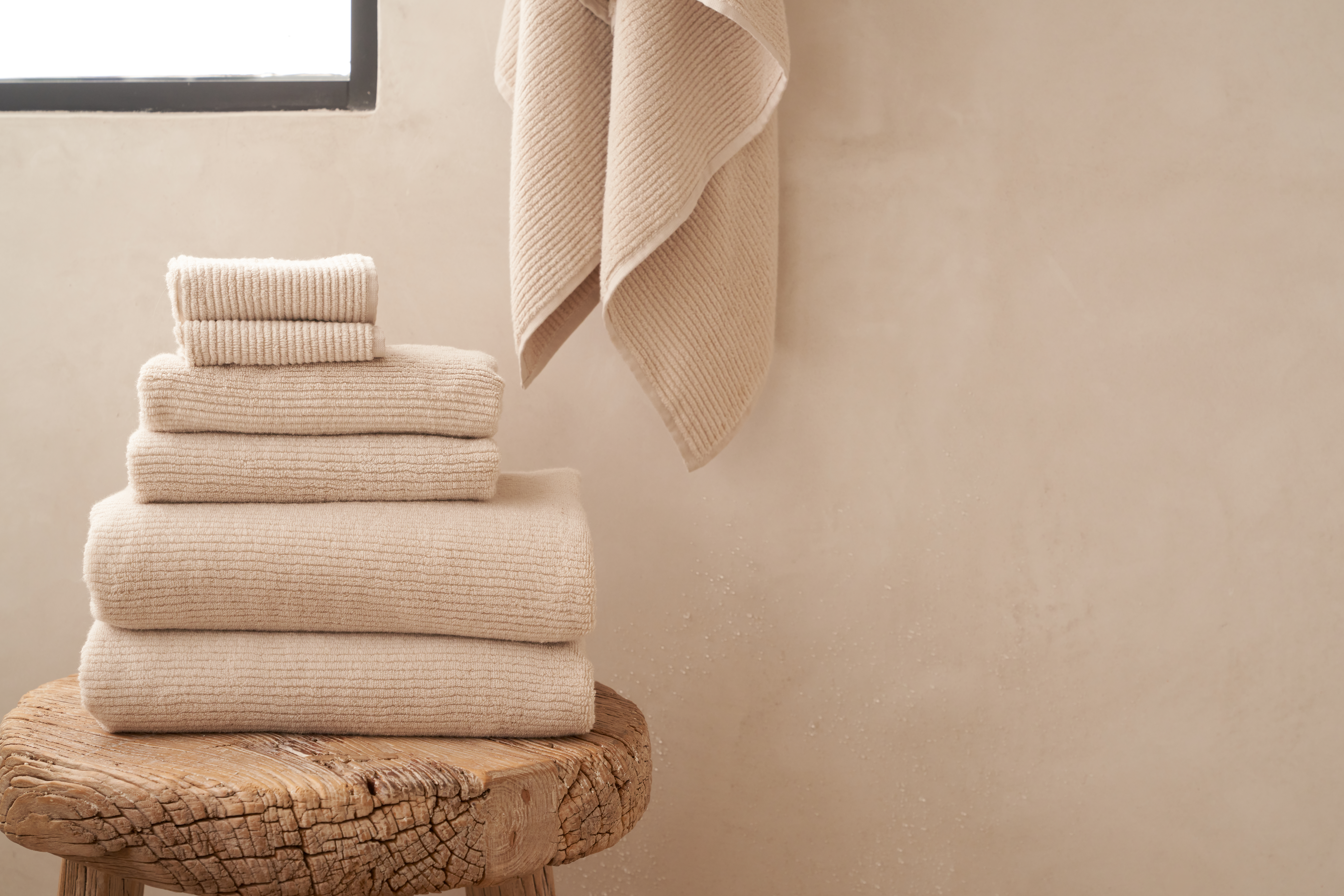 Stack of Bone Soft Rib Towels on a wooden bathroom stool