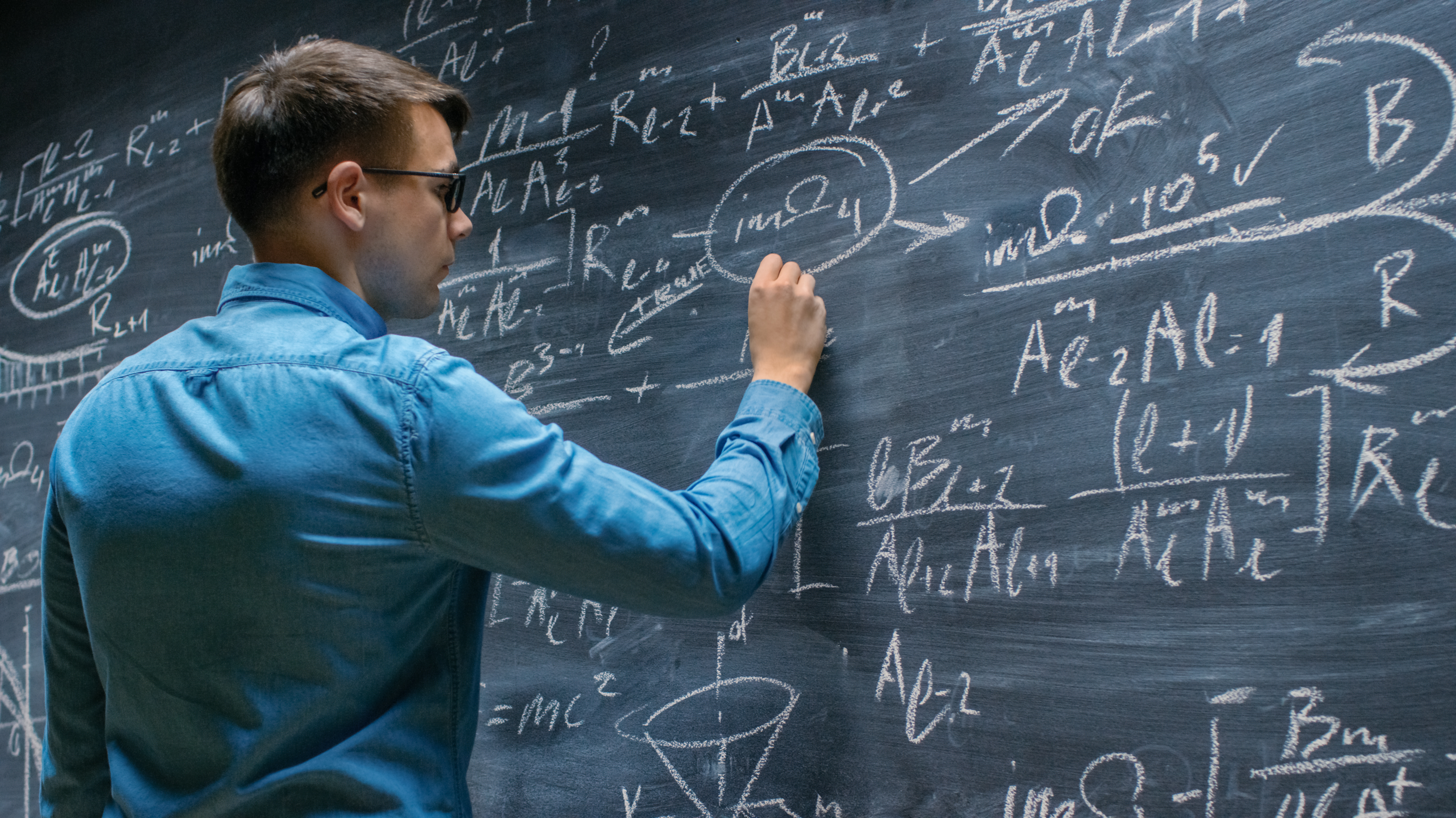 mathematician at chalk board writing equations