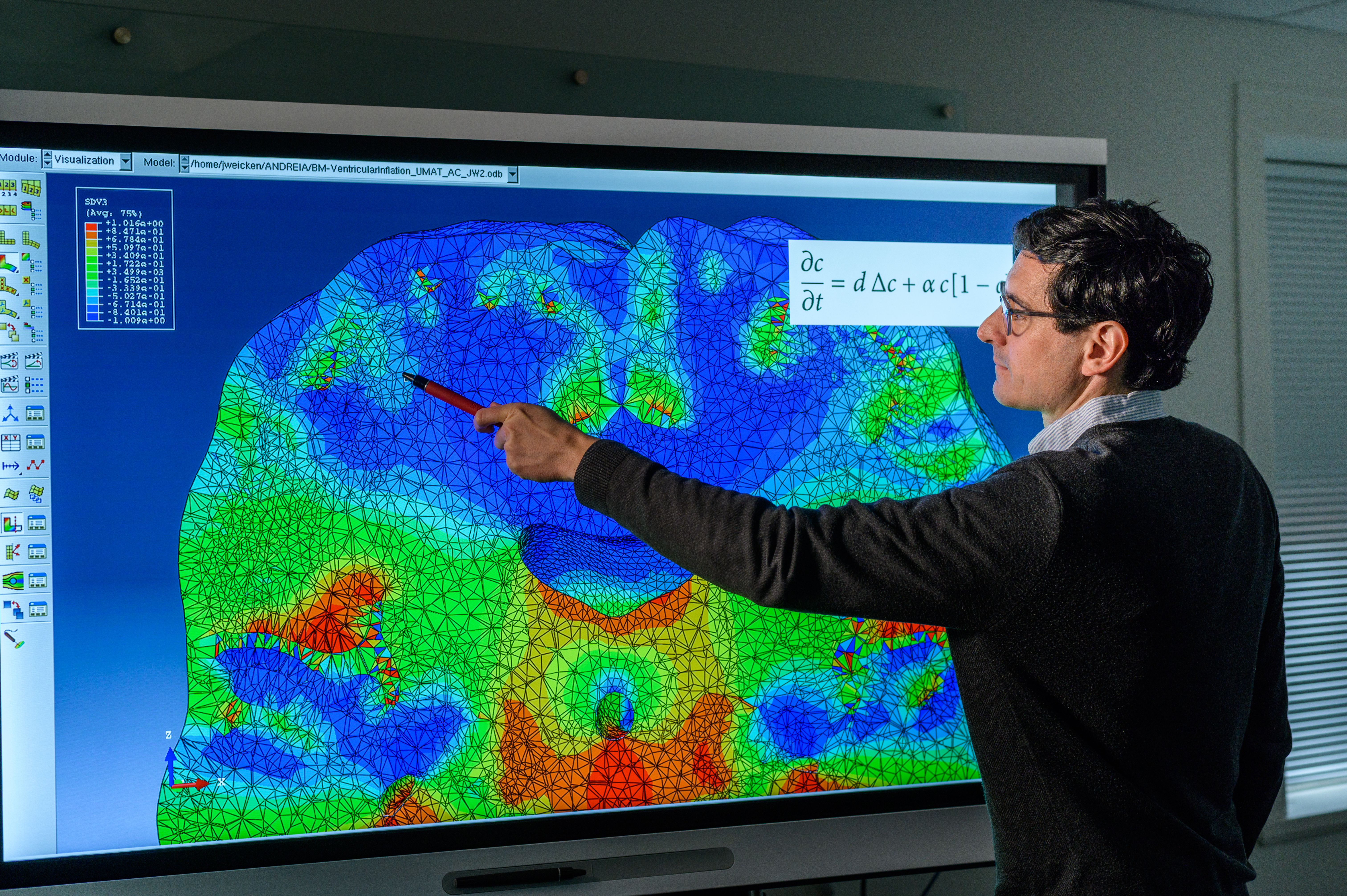 Stevens professor pointing to color image of a brain scan on large screen