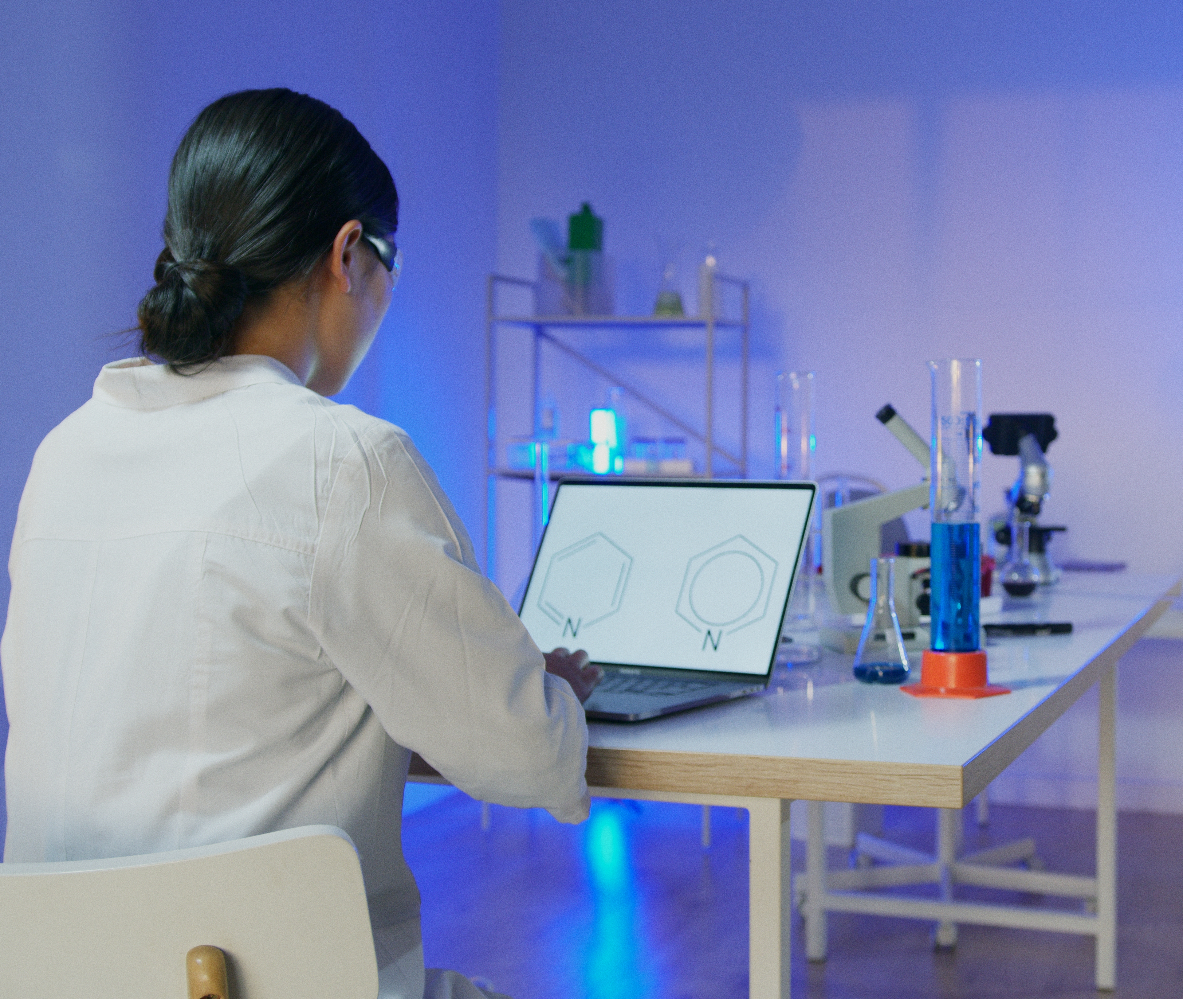Scientist working at computer with a chemical formula on the screen