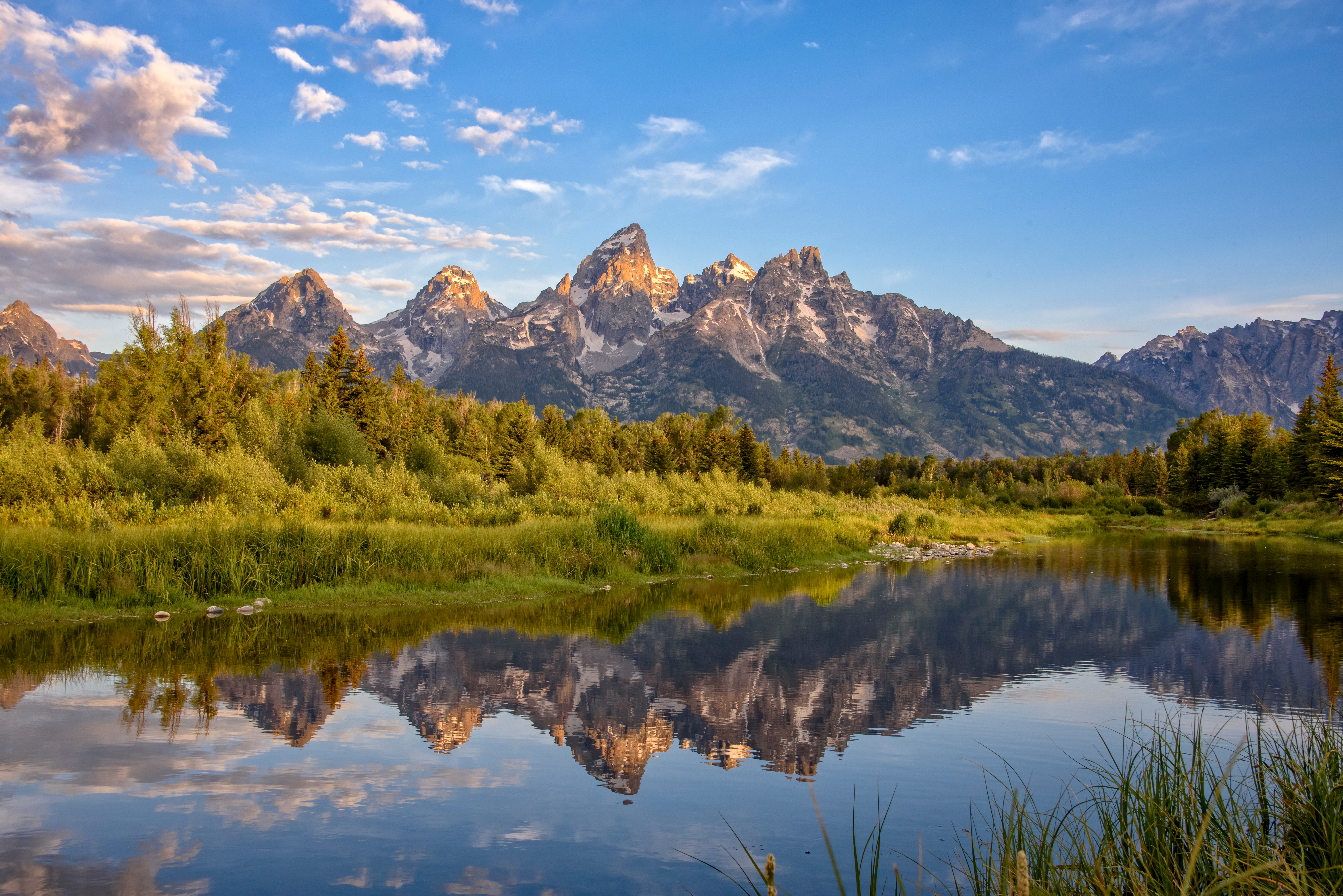 The Teton Range reflected in a tranquil lake showcases the natural beauty that attracts artists and collectors alike to Jackson Hole.