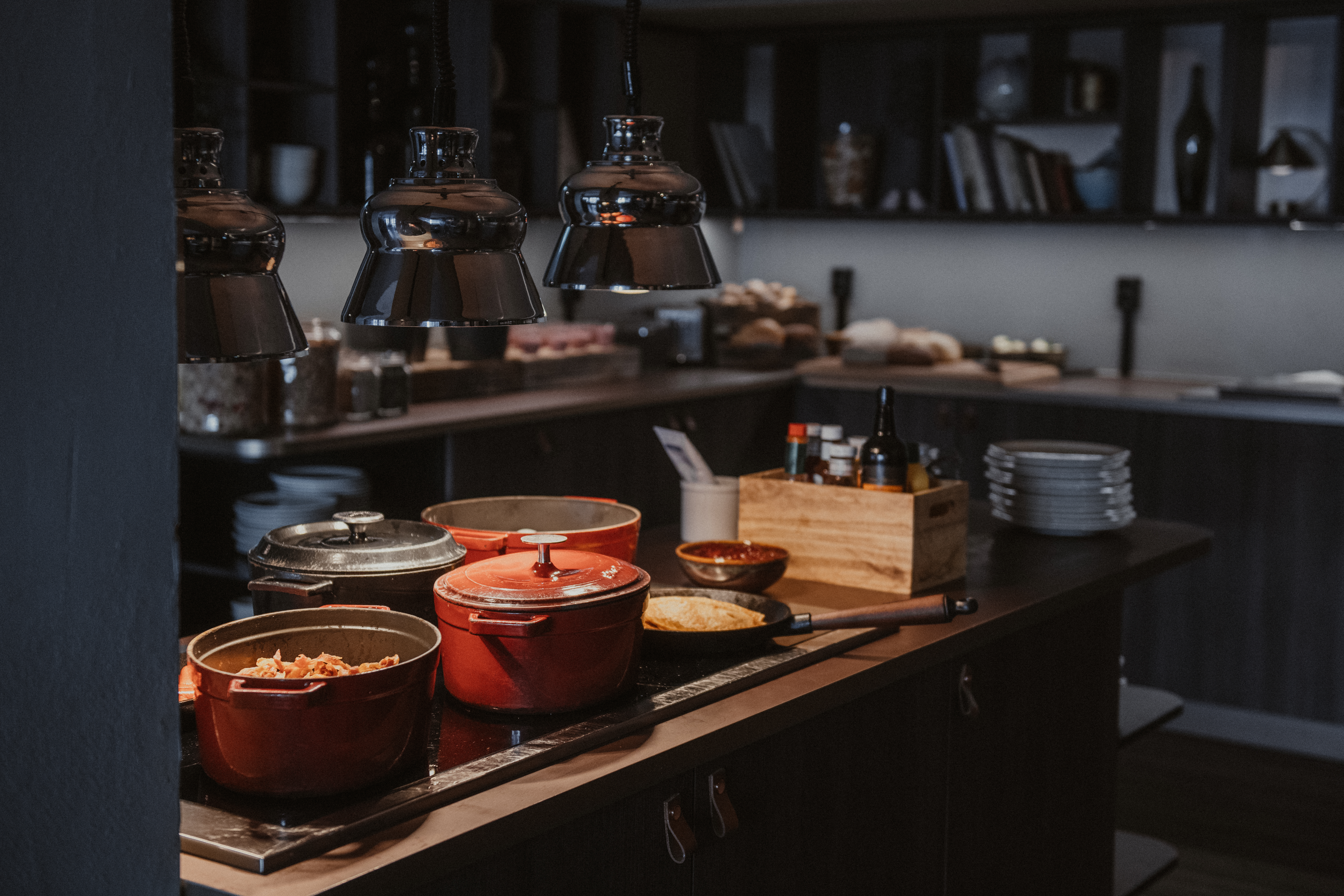 En varm och inbjudande buffé med flera varma rätter i röda grytor, redo att serveras under mjuk belysning.