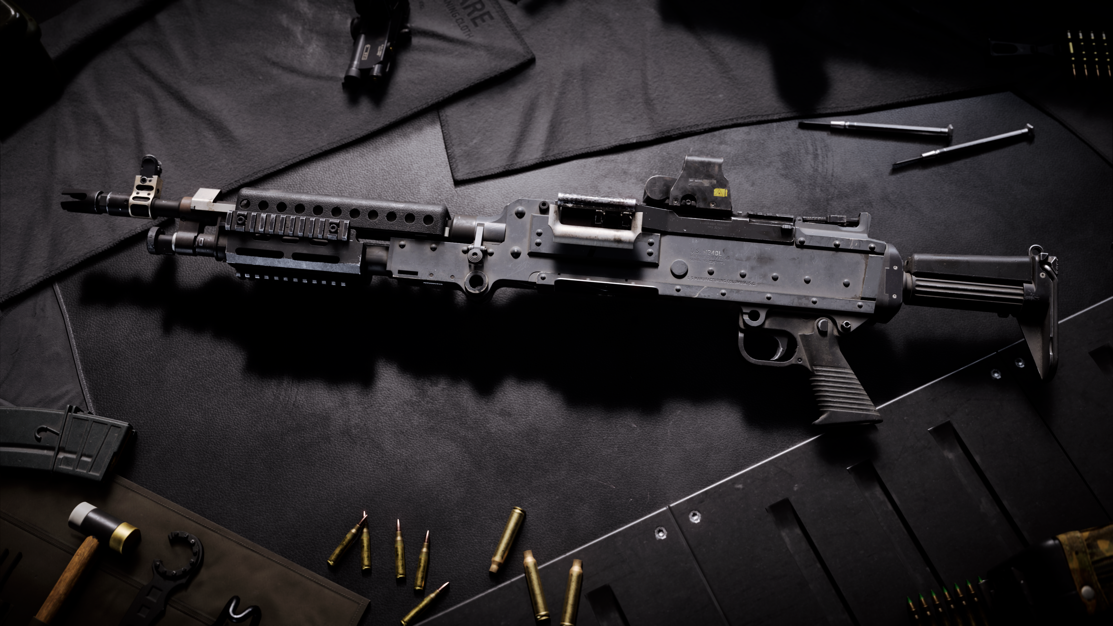 LMG M240L support weapon rests on a dark workbench surrounded by ammunition and magazines.