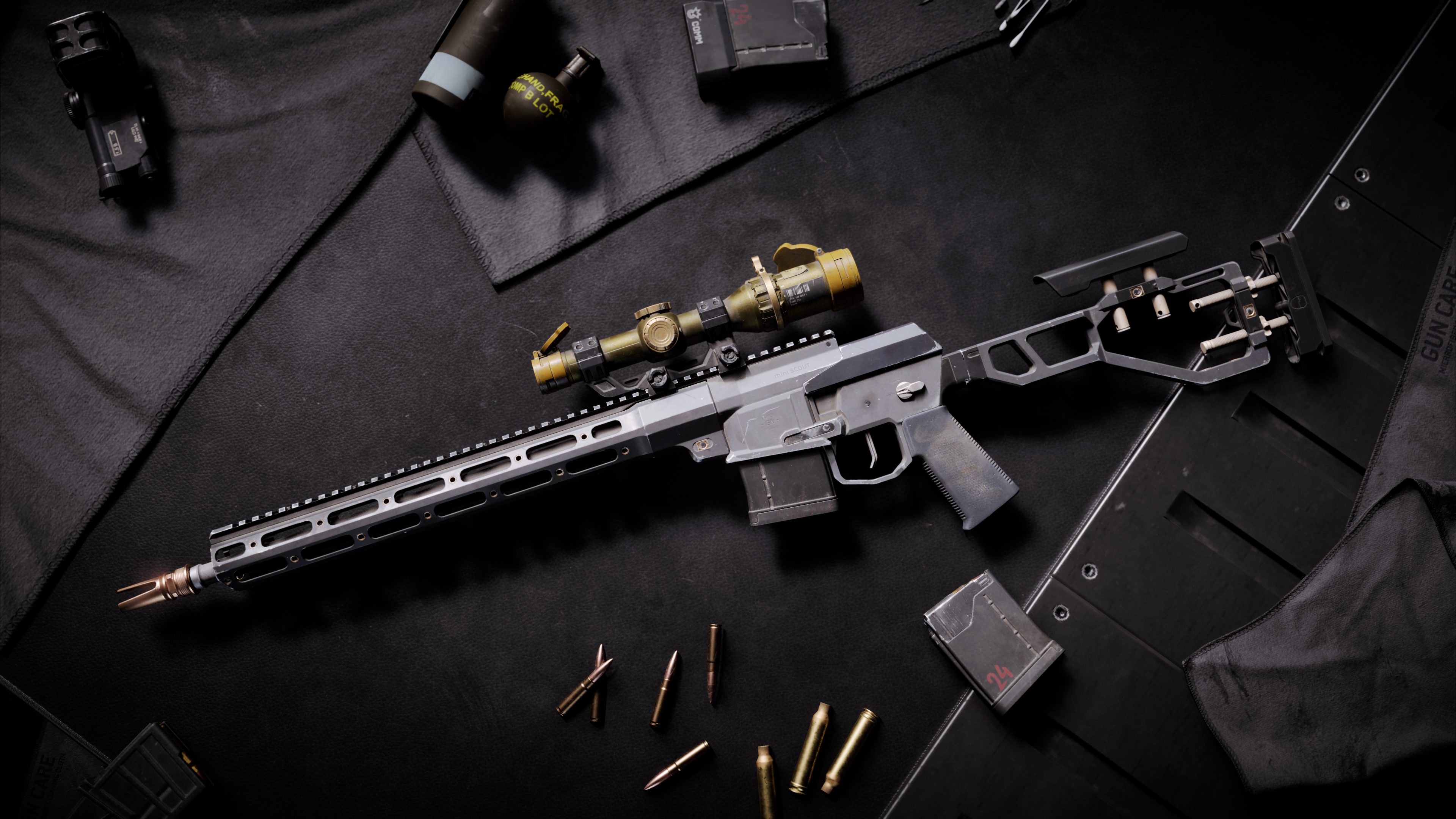 Czarny, lekki karabin snajperski Mini Scout z dodatkami leży na czarnej powierzchni, wśród nabojów i innego sprzętu taktycznego.