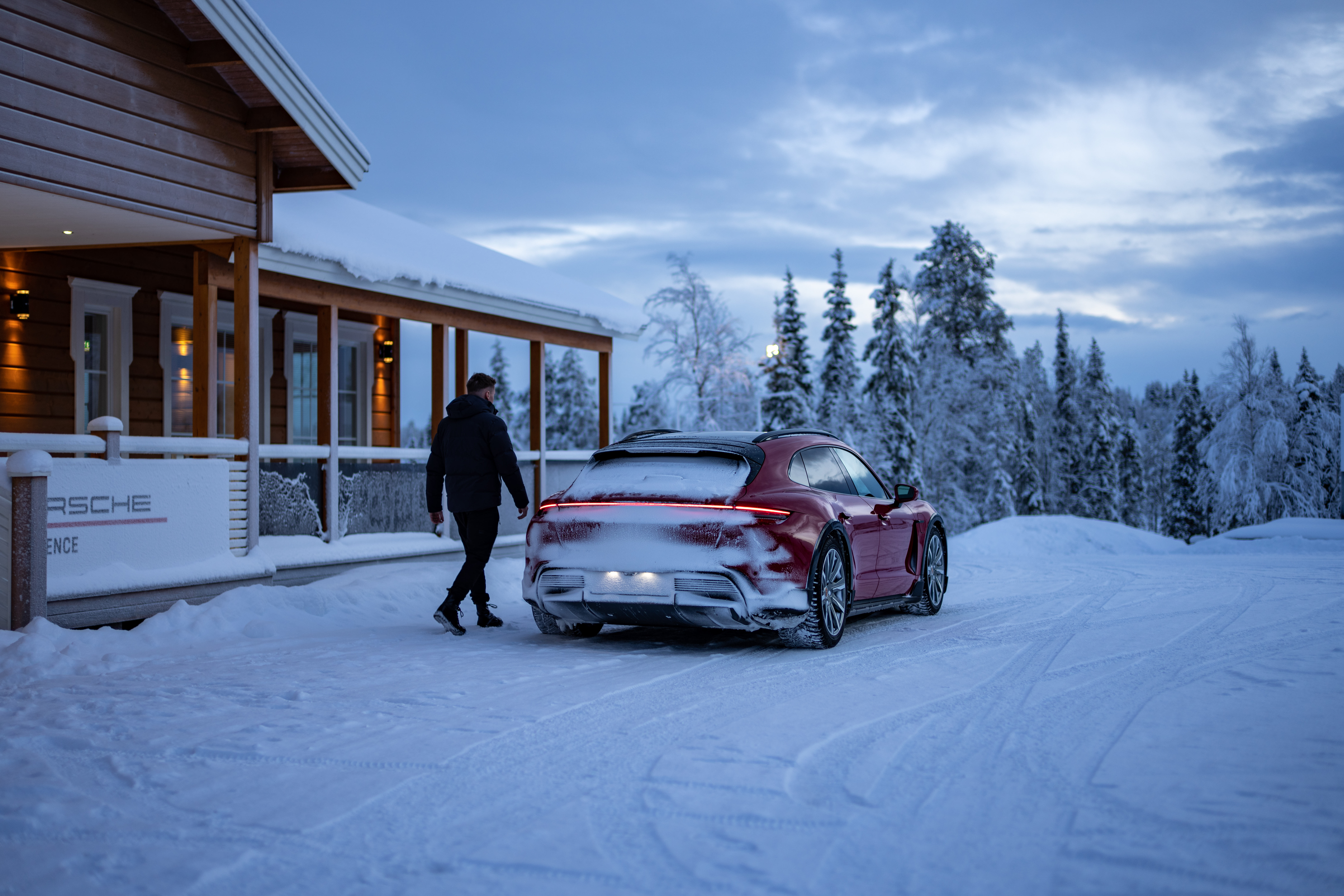 Man walks towards red Porsche Taycan in snow