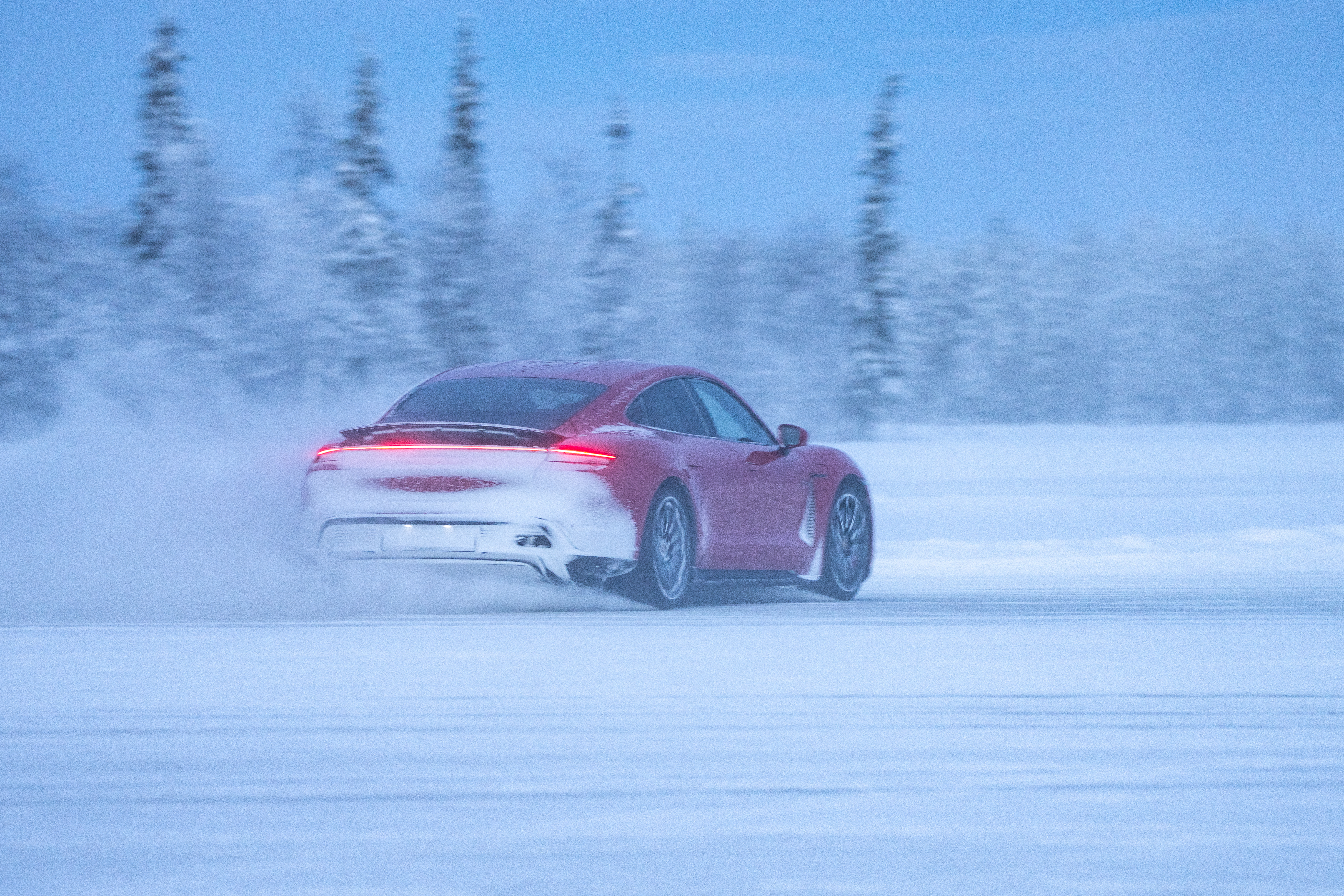 Snow kicked up by high-speed Porsche Taycan on icy field