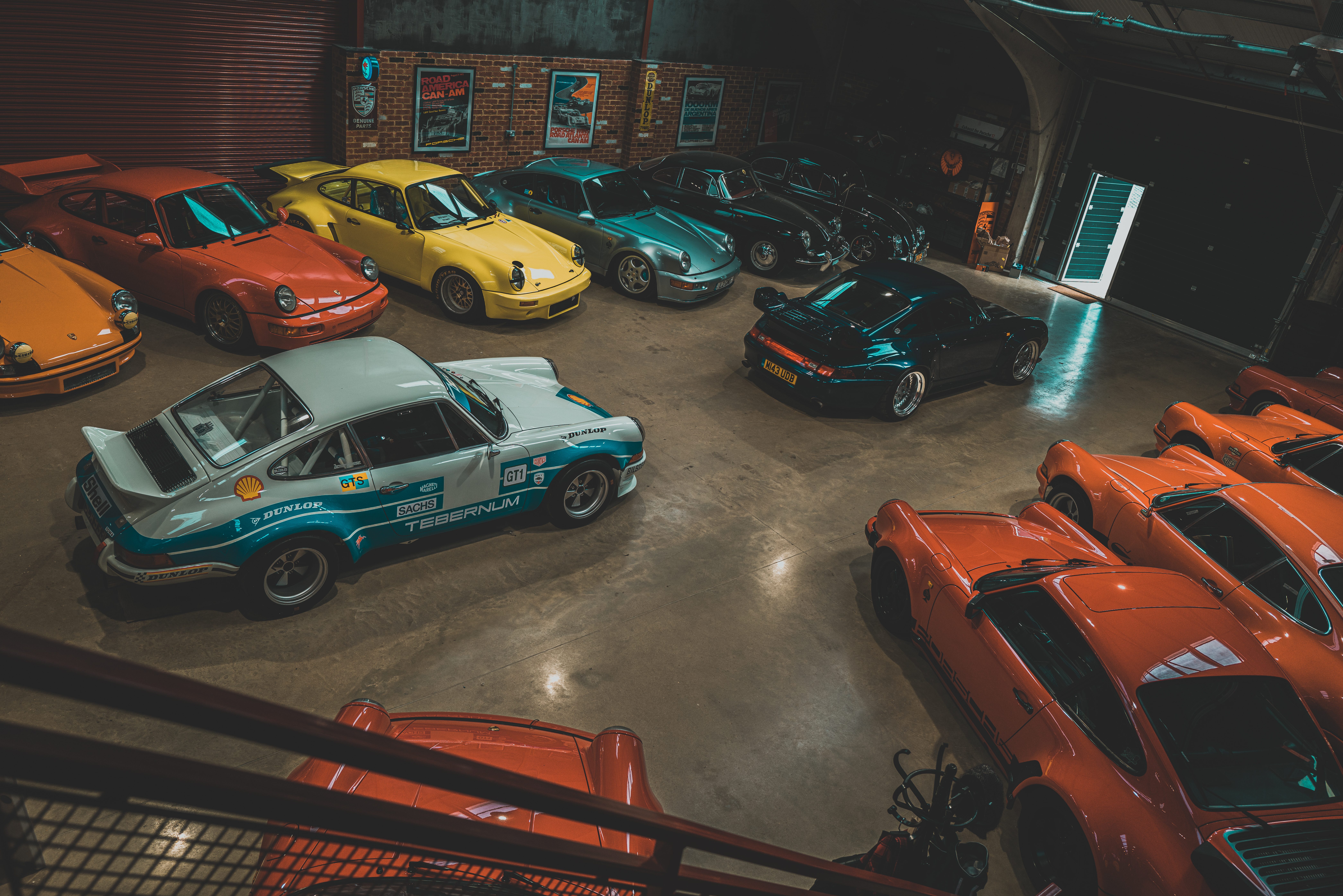 A collection of classic Porsche cars sat inside a hangar