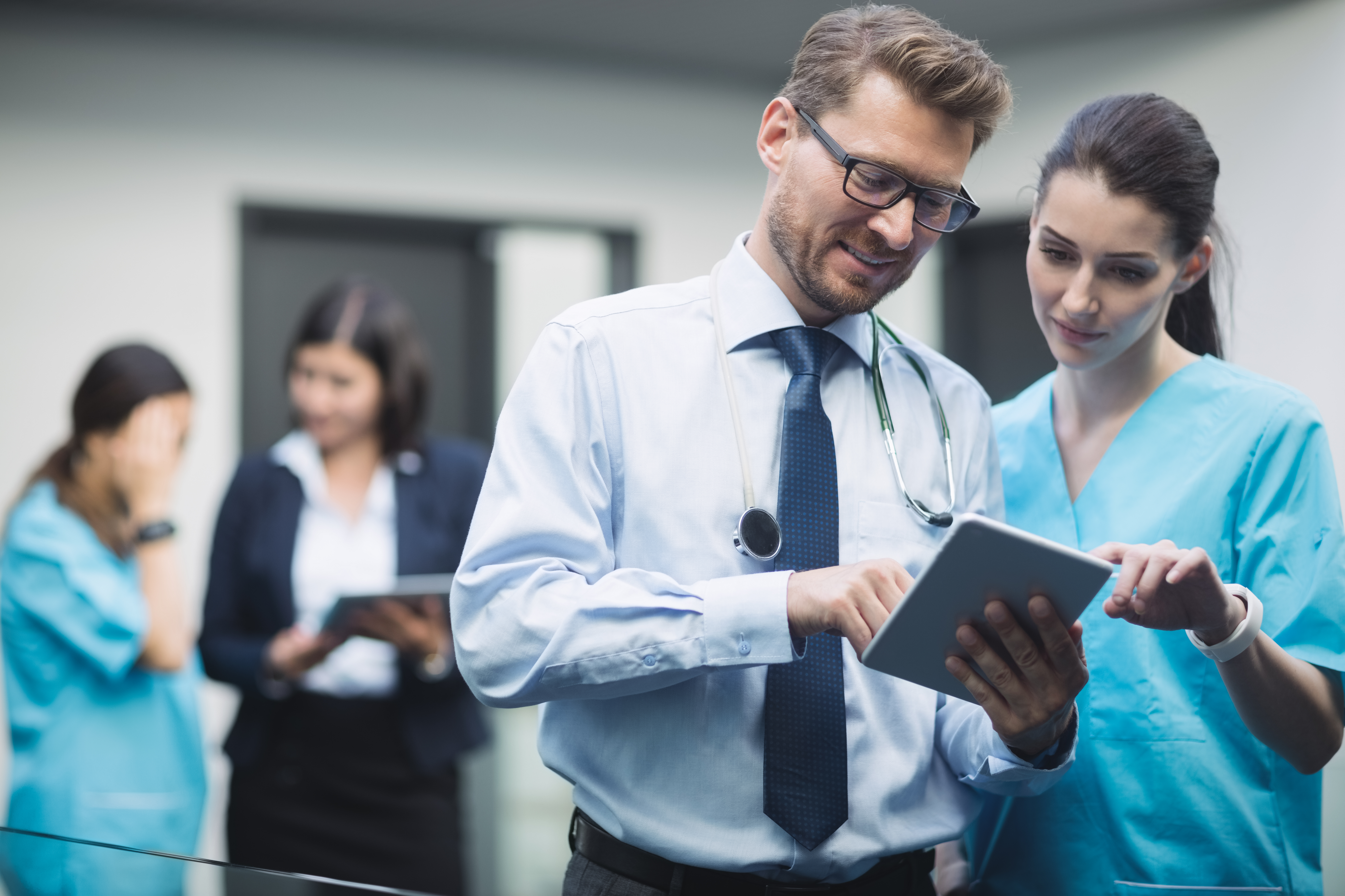 medecin-et-infirmiere-discutant-sur-tablette-numerique