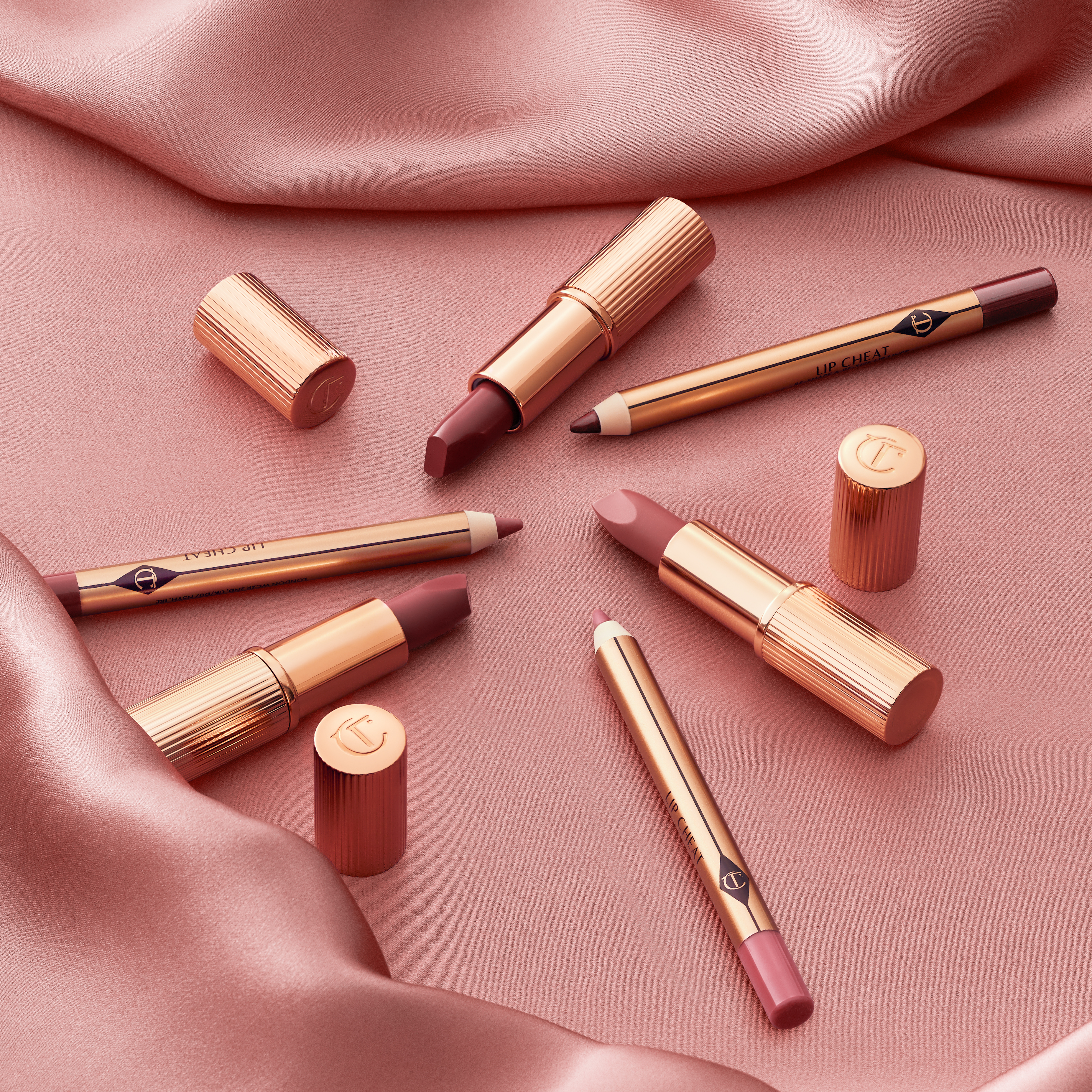 A collection of mini lipsticks and lip liners in nude pink, medium pink, and brown-pink.
