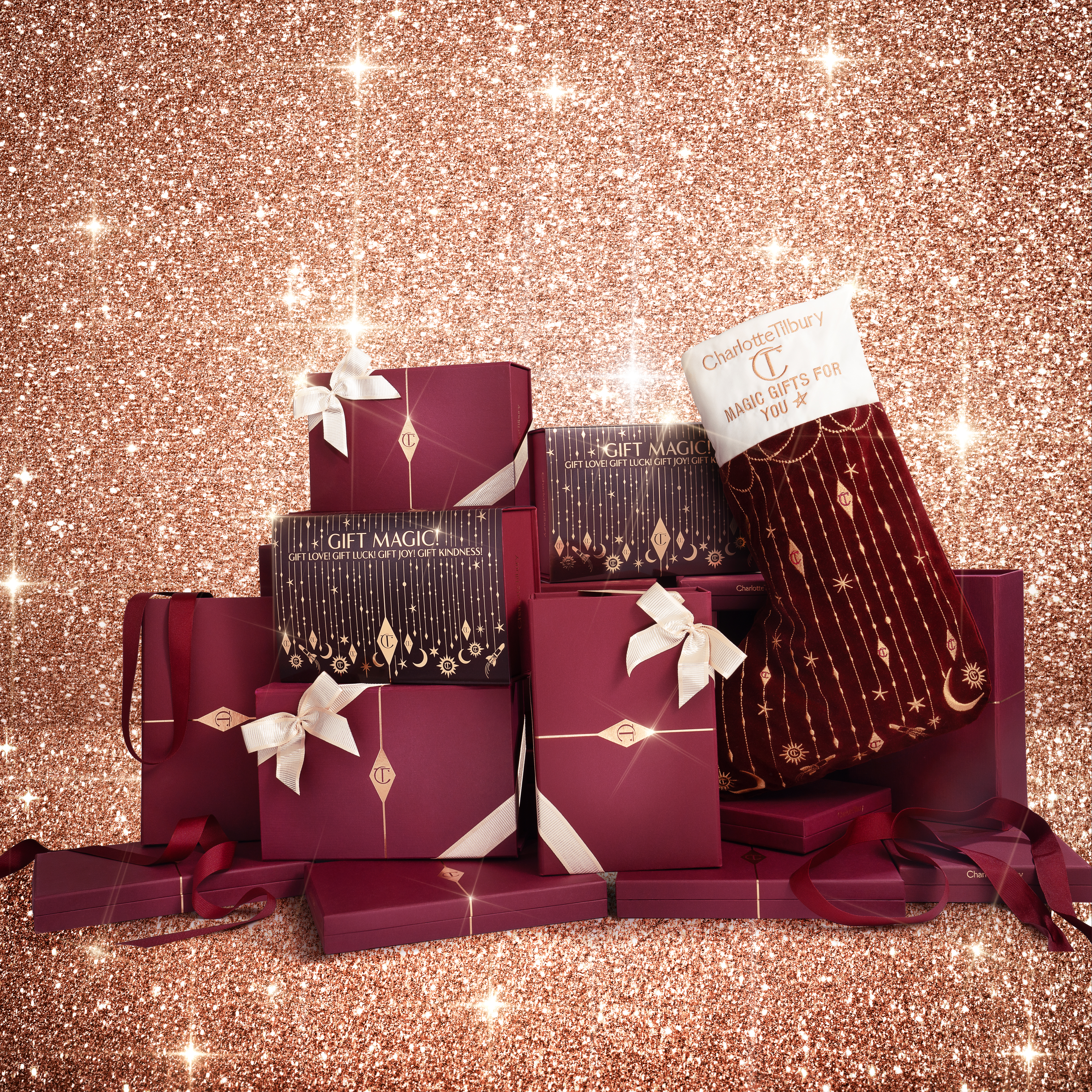 Ein großer Stapel kastanienbrauner und goldener Geschenkschachteln mit cremefarbenen Bändern, dazu verzierte Weihnachtsstrümpfe.