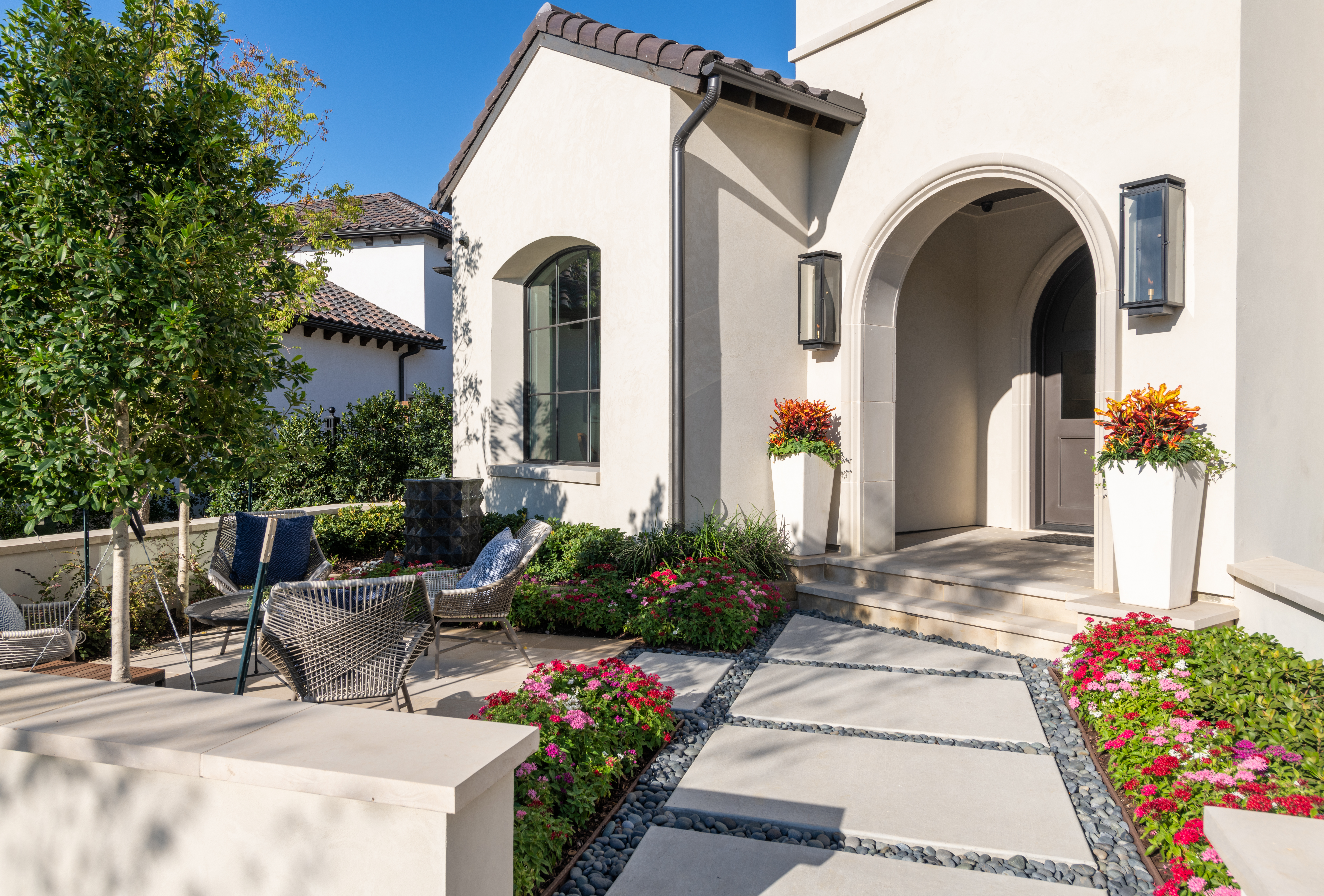 White stucco entryway with potted flowers and arched doorway