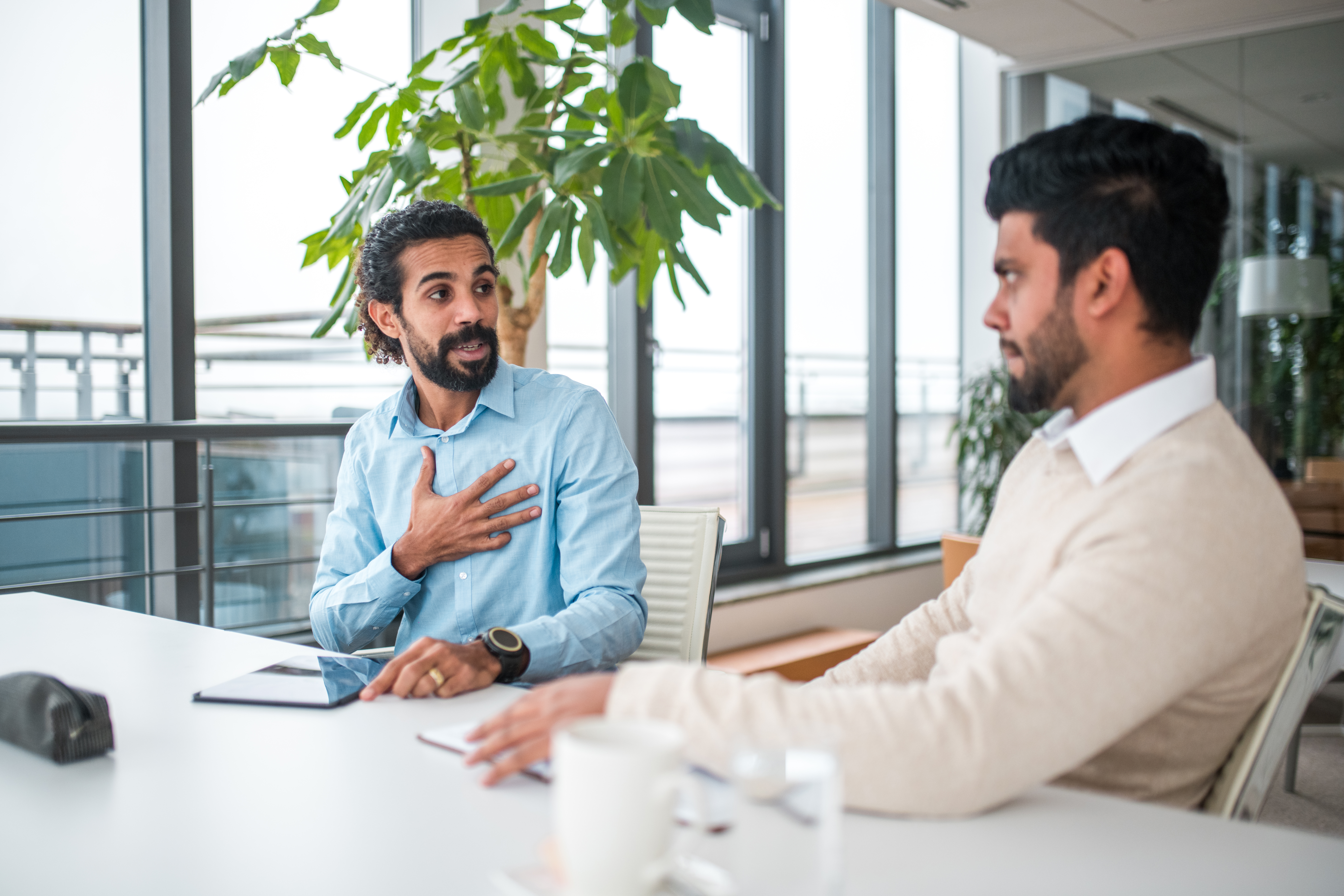 [Featured Image] A human resources manager reviews HR specialist salary information with a new hire at a conference table.