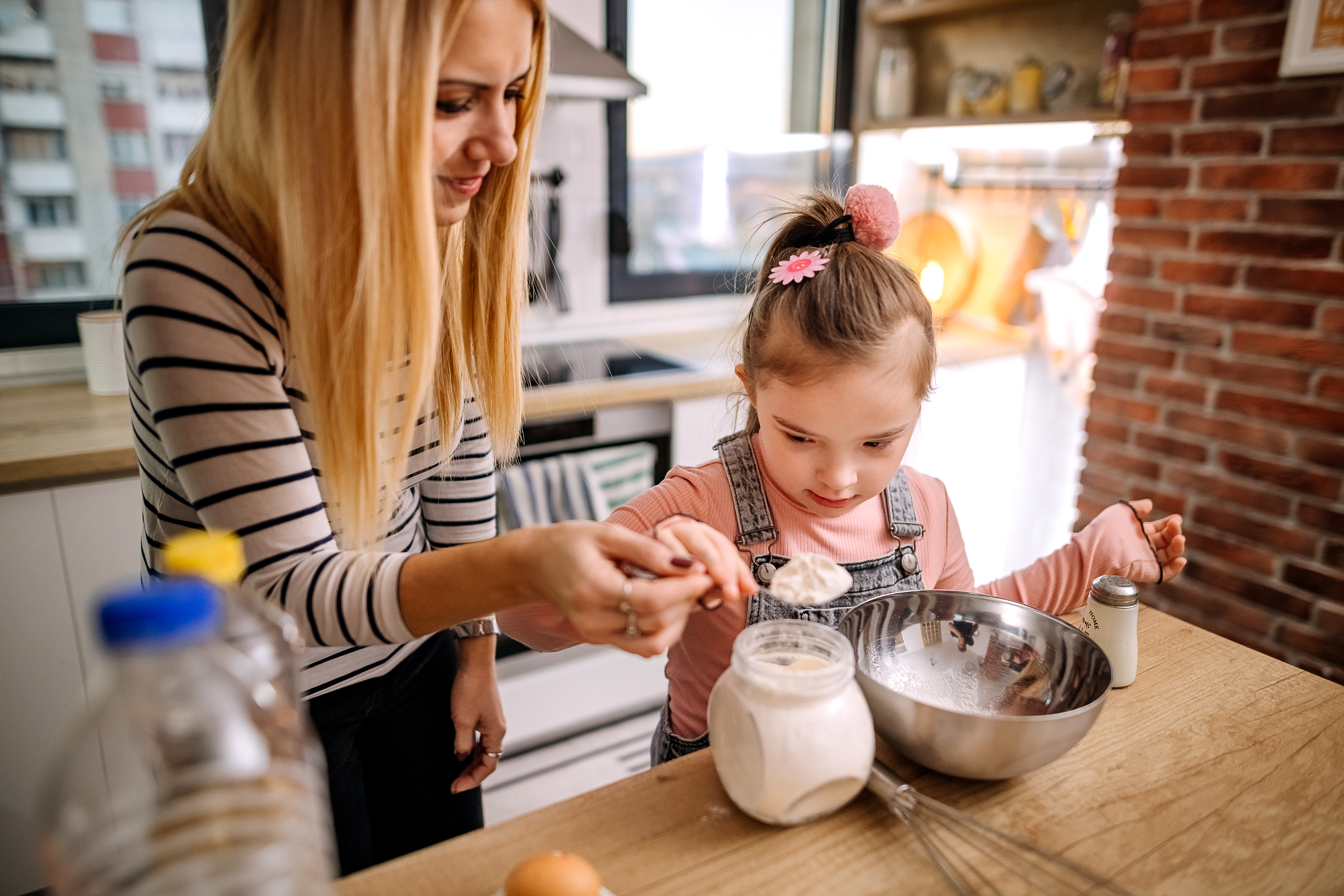 Tânără femeie și copil gătesc împreună