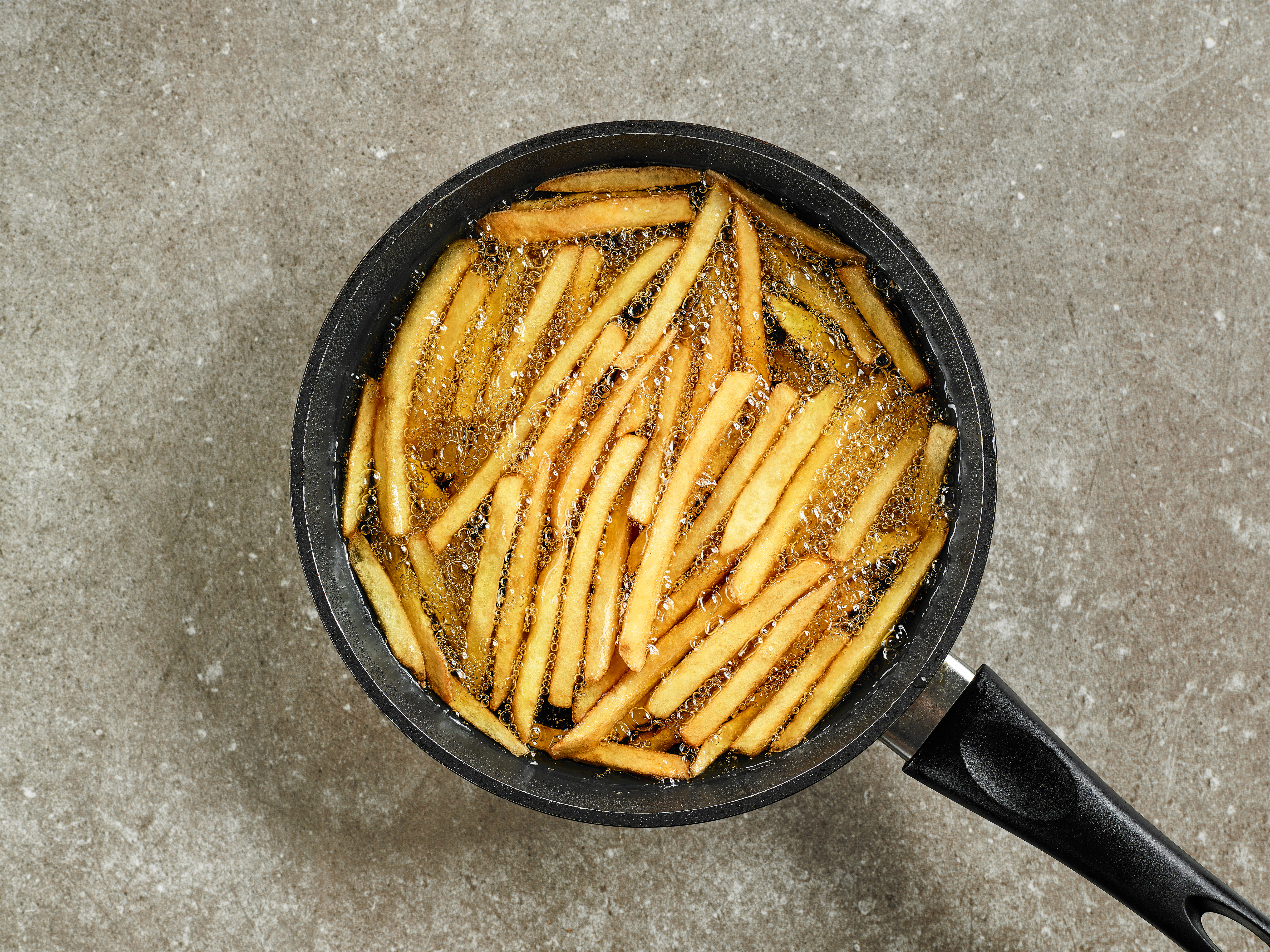 Pommes frites i olja i stekpanna - shutterstock 1133067398