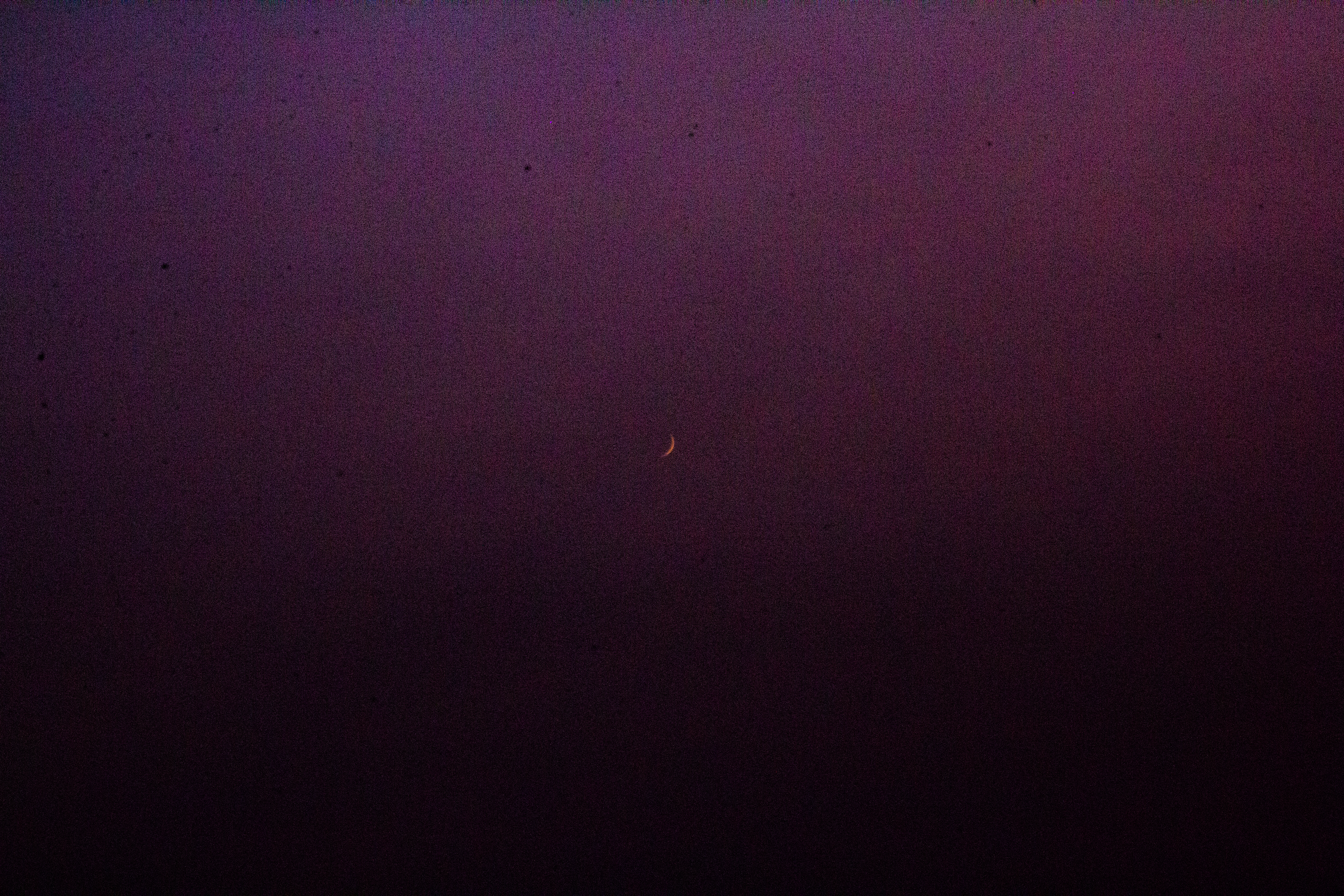 A photograph of the moon, a small crescent in the distance.